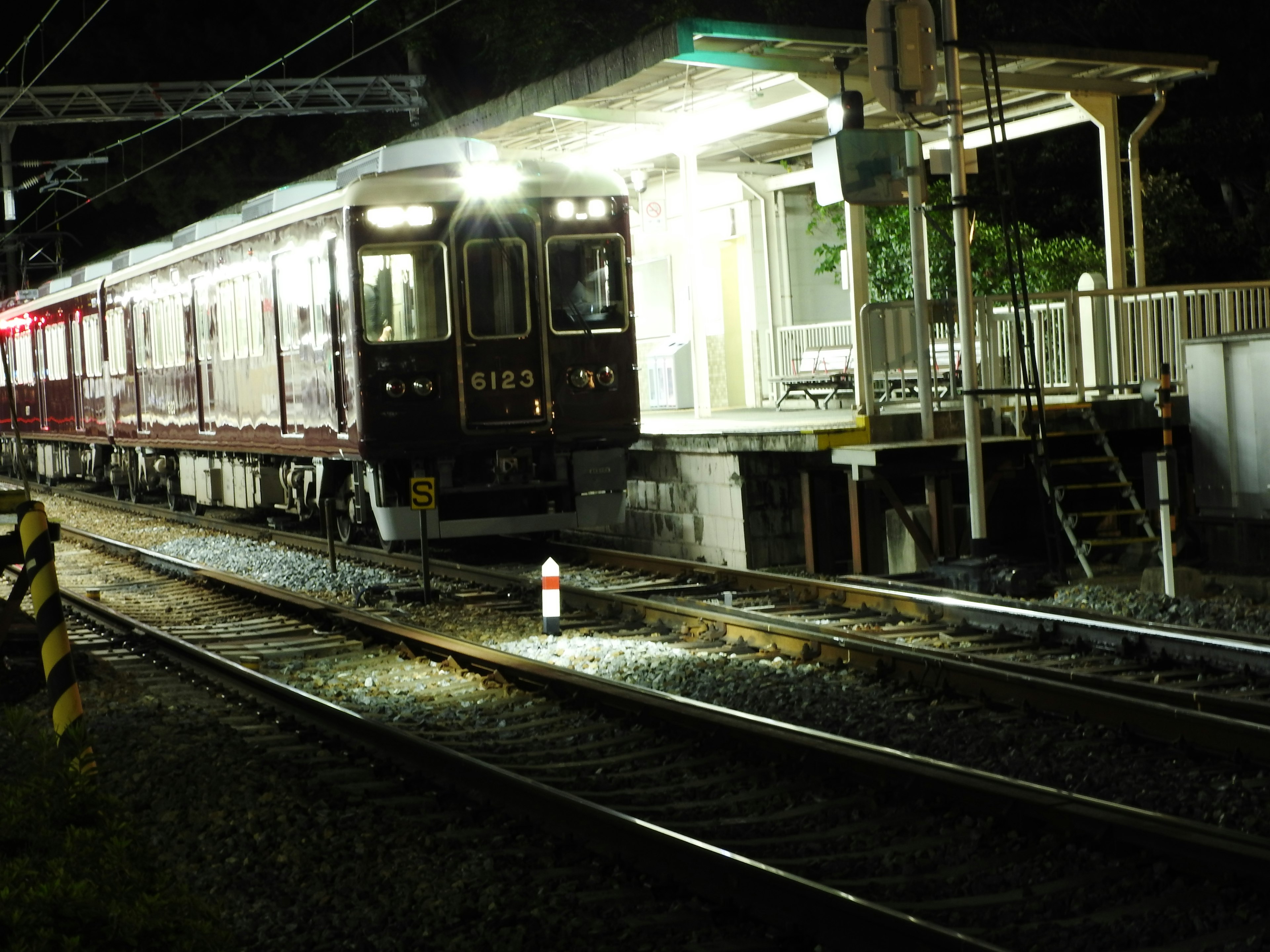 รถไฟสีแดงจอดที่สถานีในเวลากลางคืนพร้อมอาคารสถานีที่สว่าง