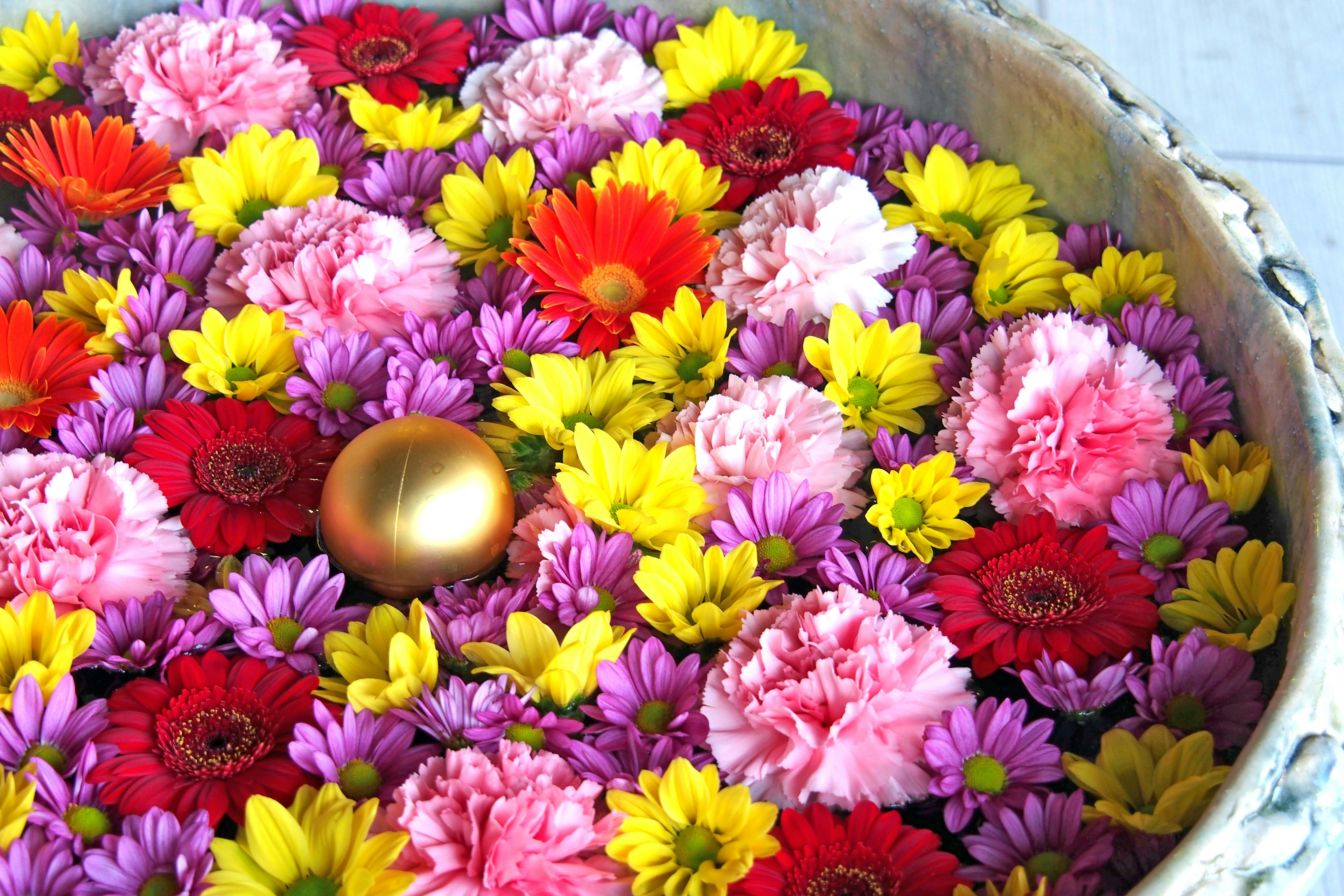 Colorful flowers floating in a bowl with a golden ball