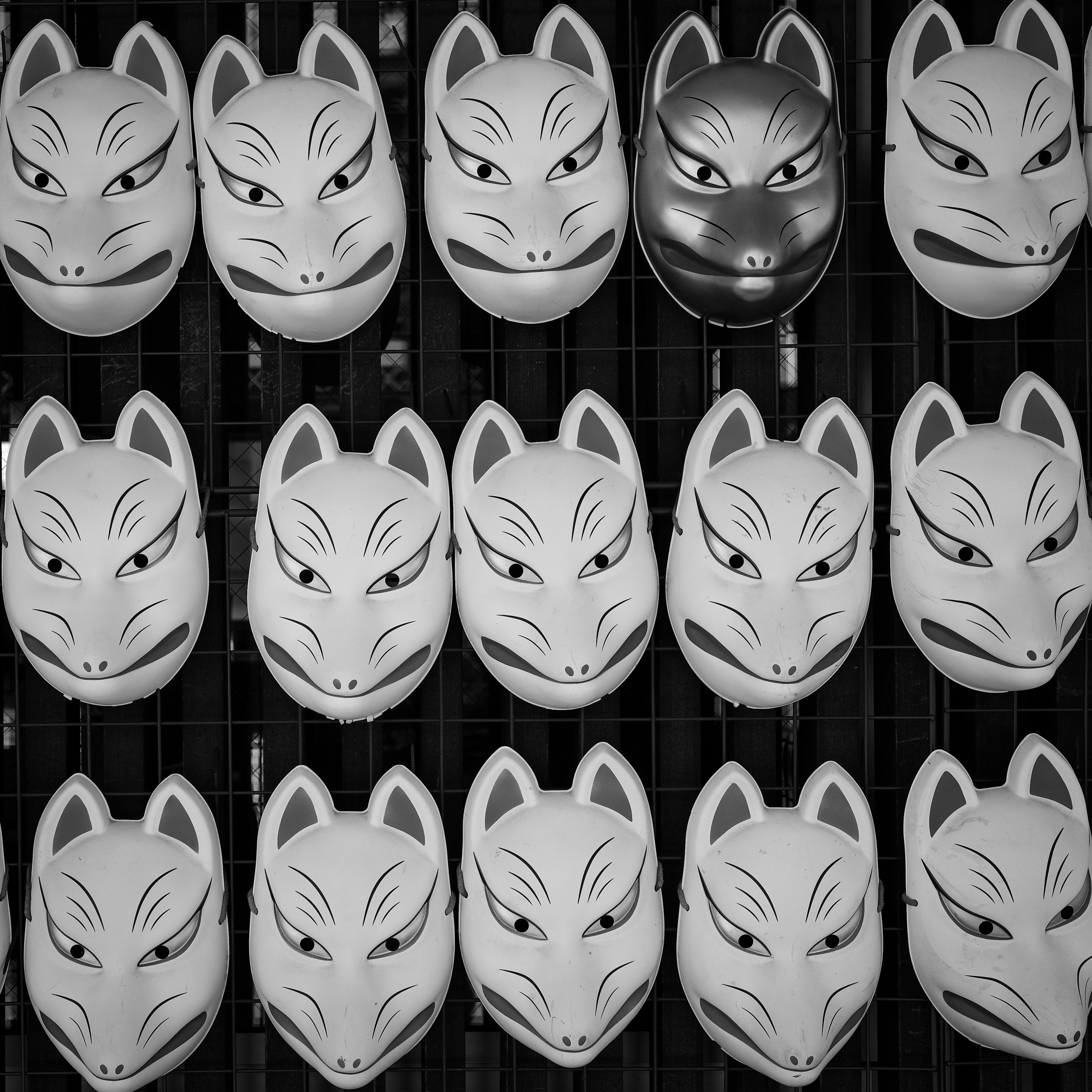 Ein monochromes Bild mit mehreren weißen Fuchs-Masken in einem Raster angeordnet