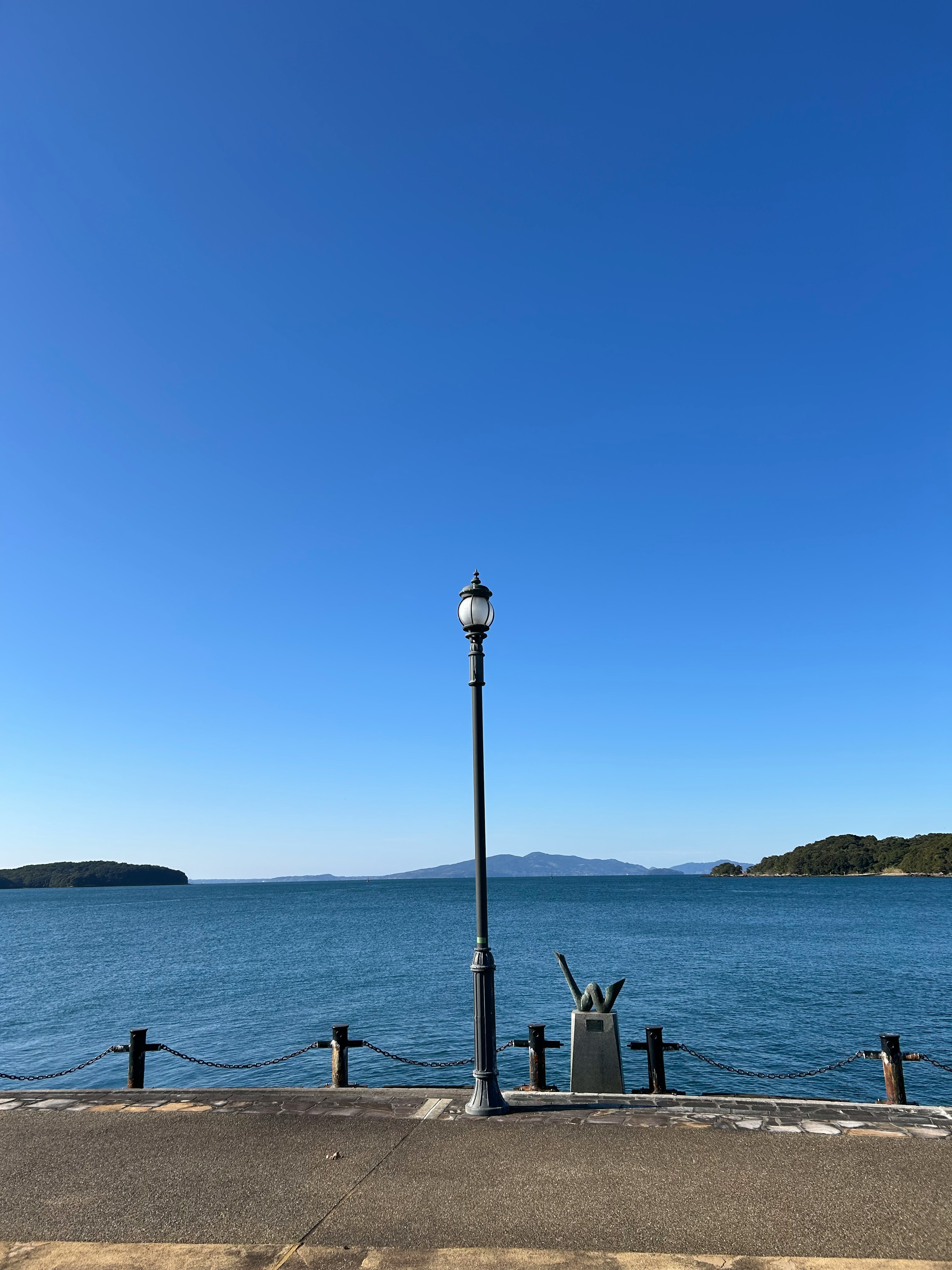 青空と海の景色に立つ街灯の画像