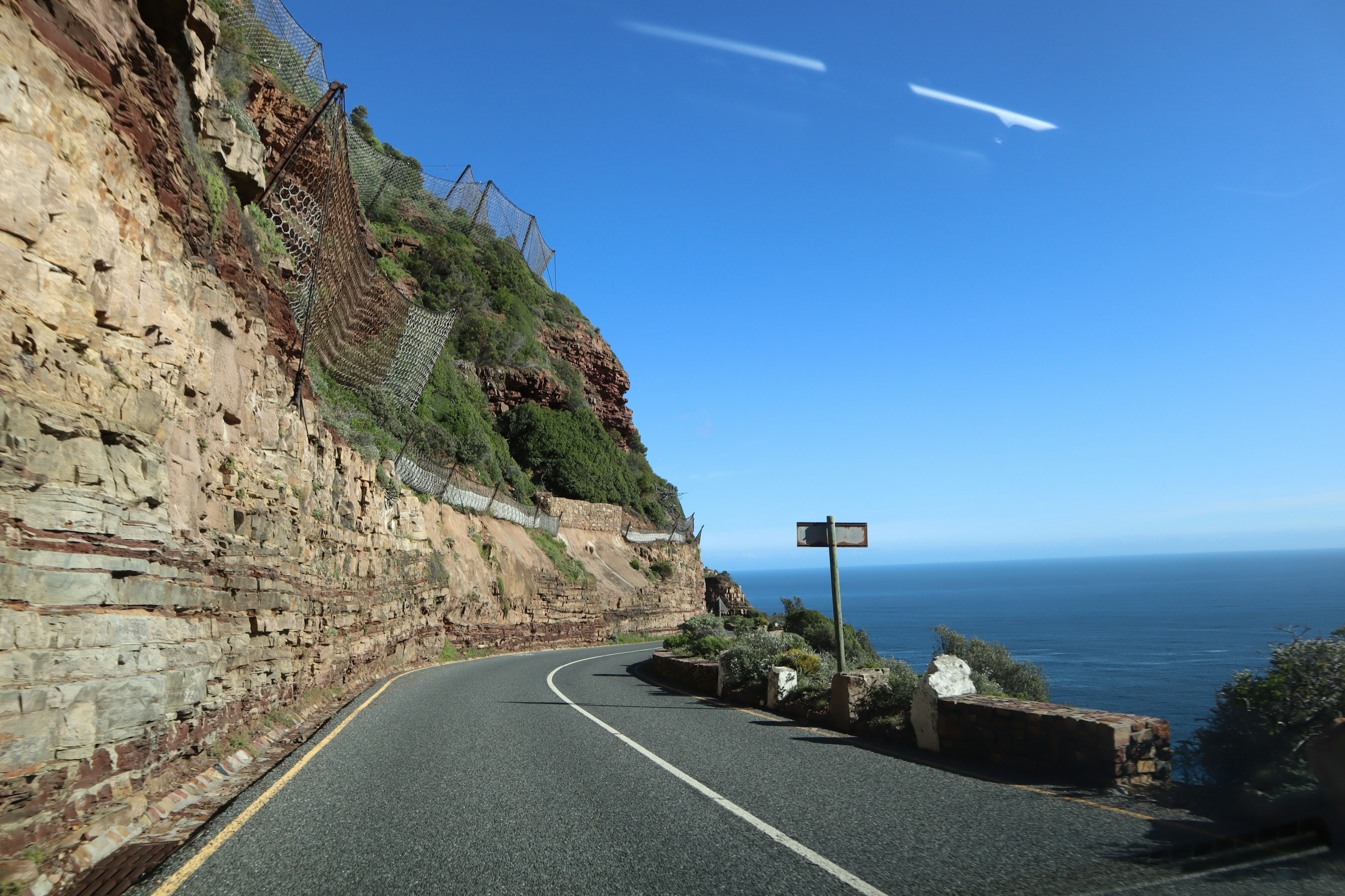 Scenic coastal road winding along a rocky cliff with ocean views