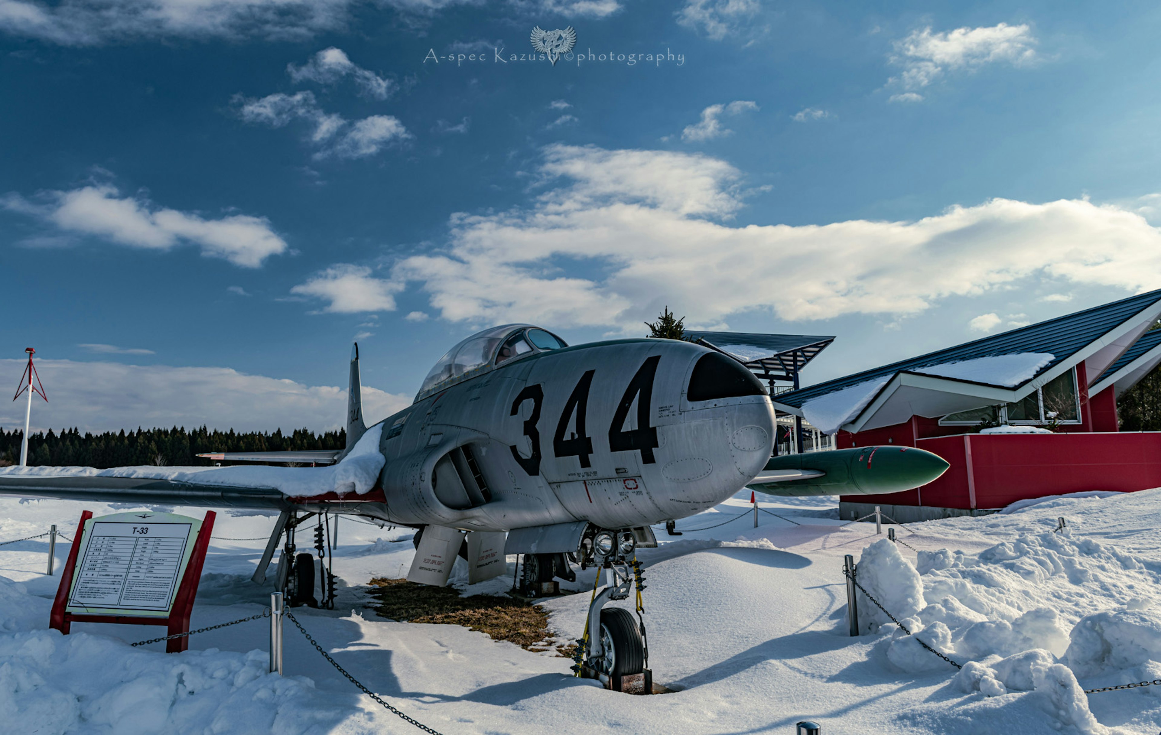 雪に覆われた滑走路に展示された戦闘機344号機周囲の青空と雲