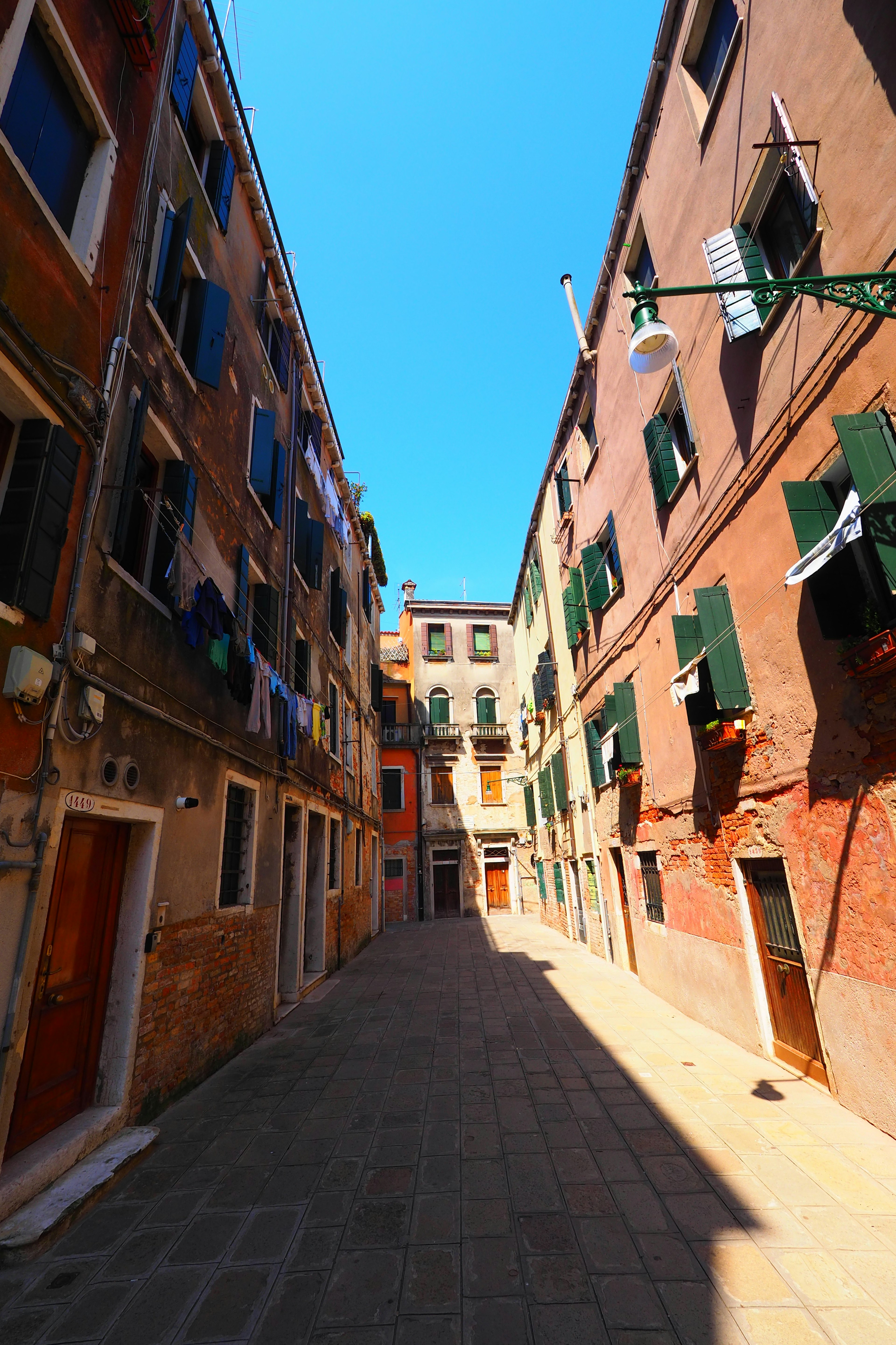 Narrow street in Venice under a bright blue sky with colorful buildings