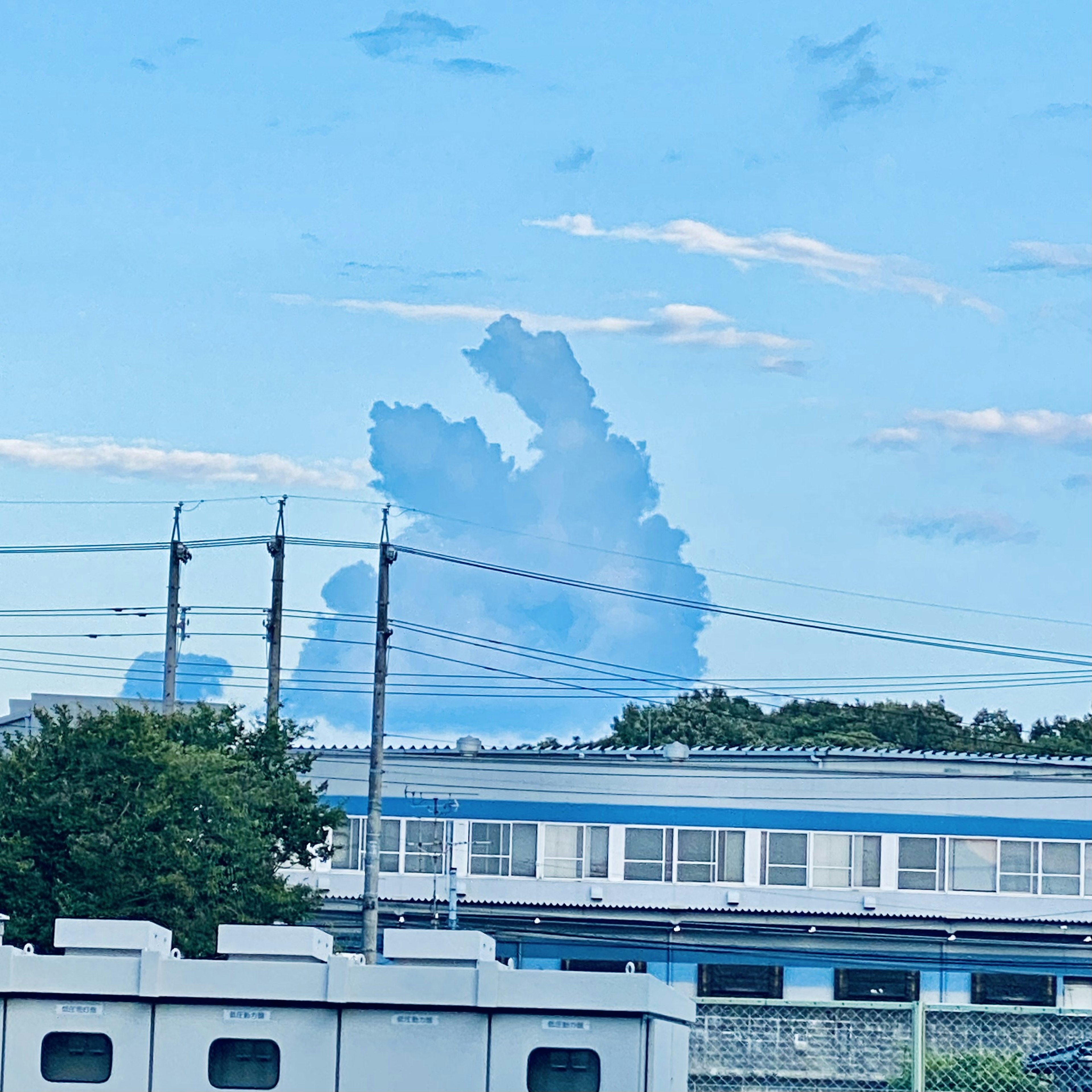 Unique cloud formation in a blue sky with buildings below