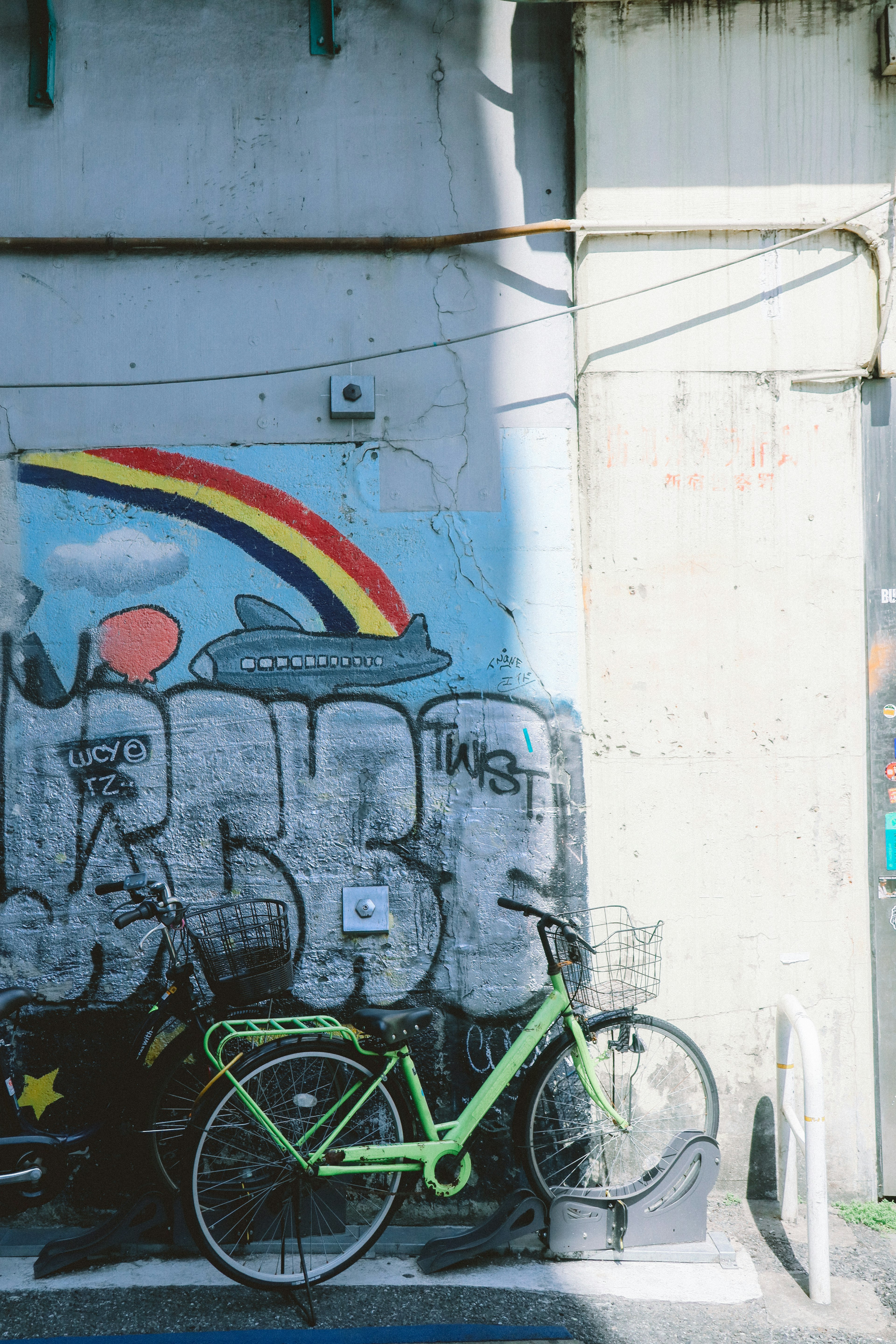 Bicicletta verde contro un muro di graffiti colorato