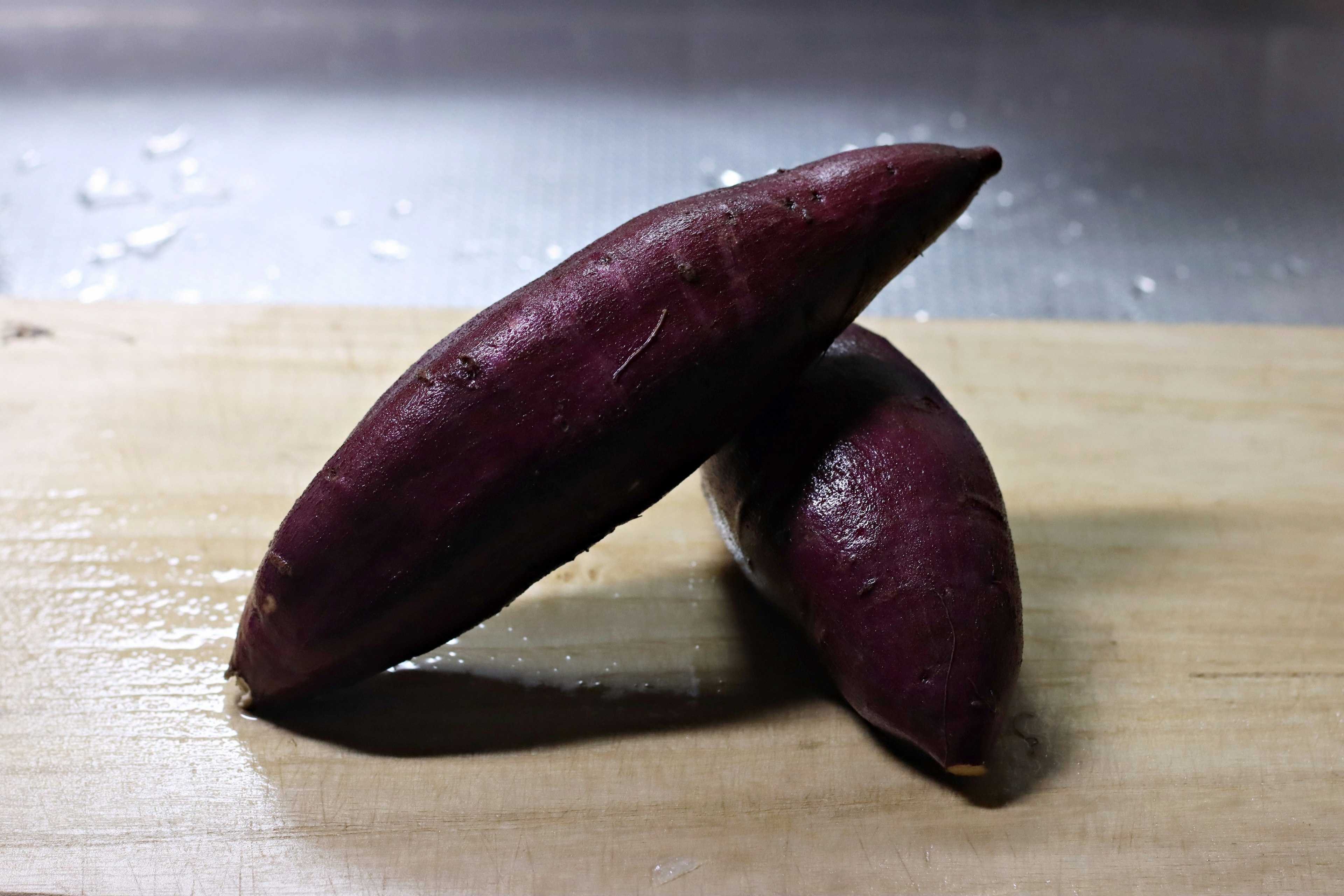 Dos batatas moradas descansando sobre una superficie de madera