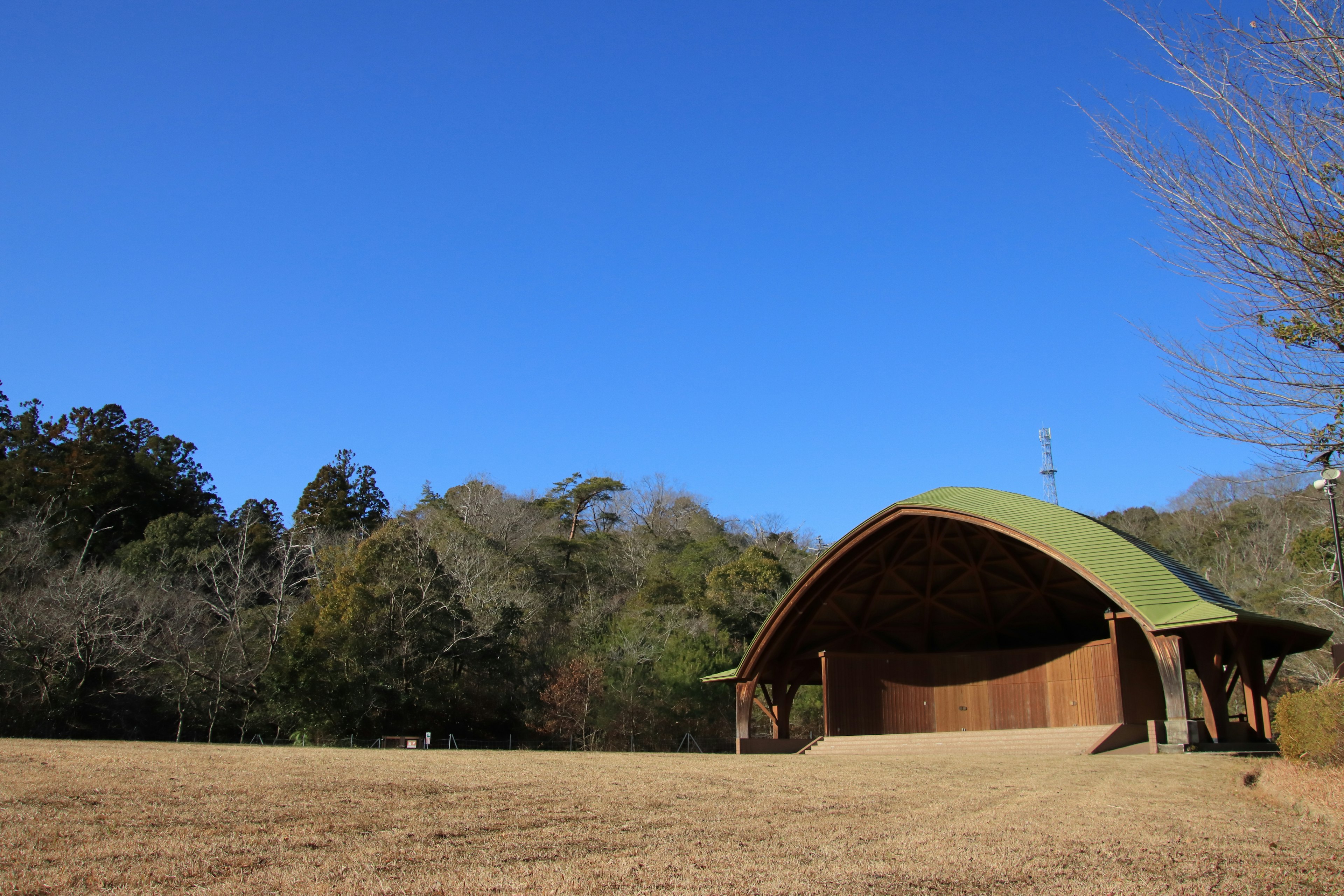 緑色の屋根を持つ木造の野外ステージと青い空