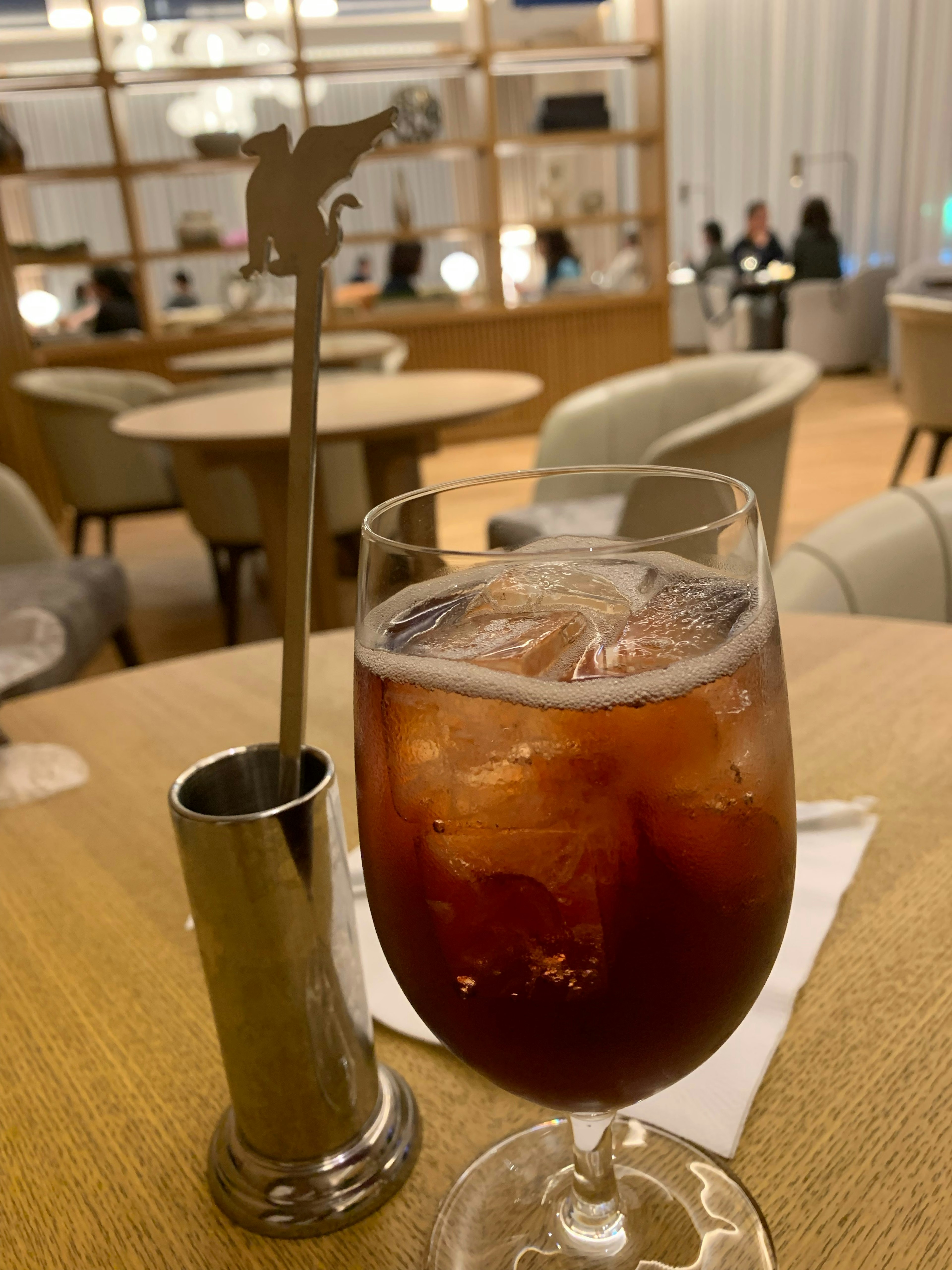 Una escena de bar elegante con una bebida con hielo y un mezclador único sobre una mesa de madera