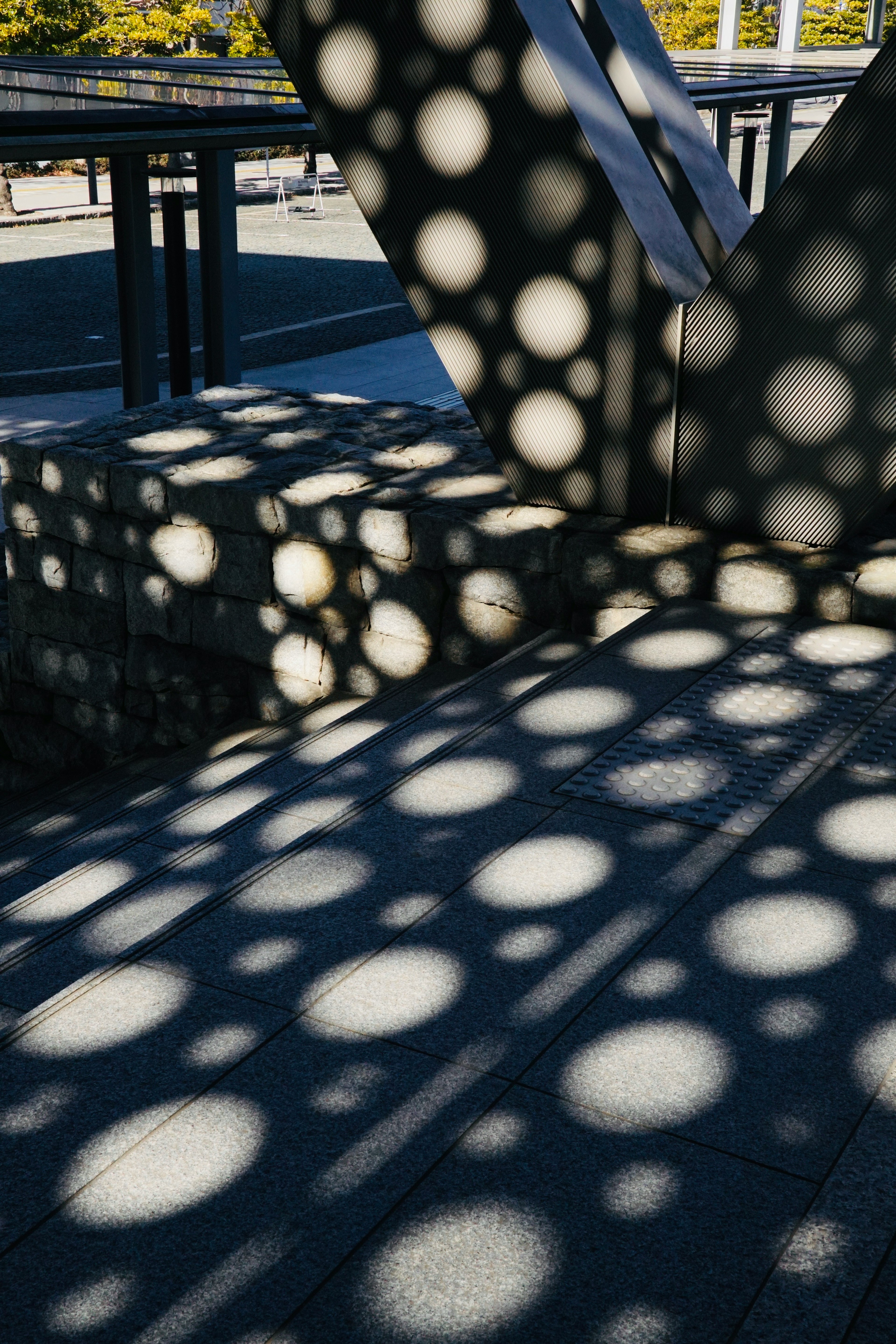 Betontreppen und Metallstruktur mit kreisförmigen Schatten vom Sonnenlicht