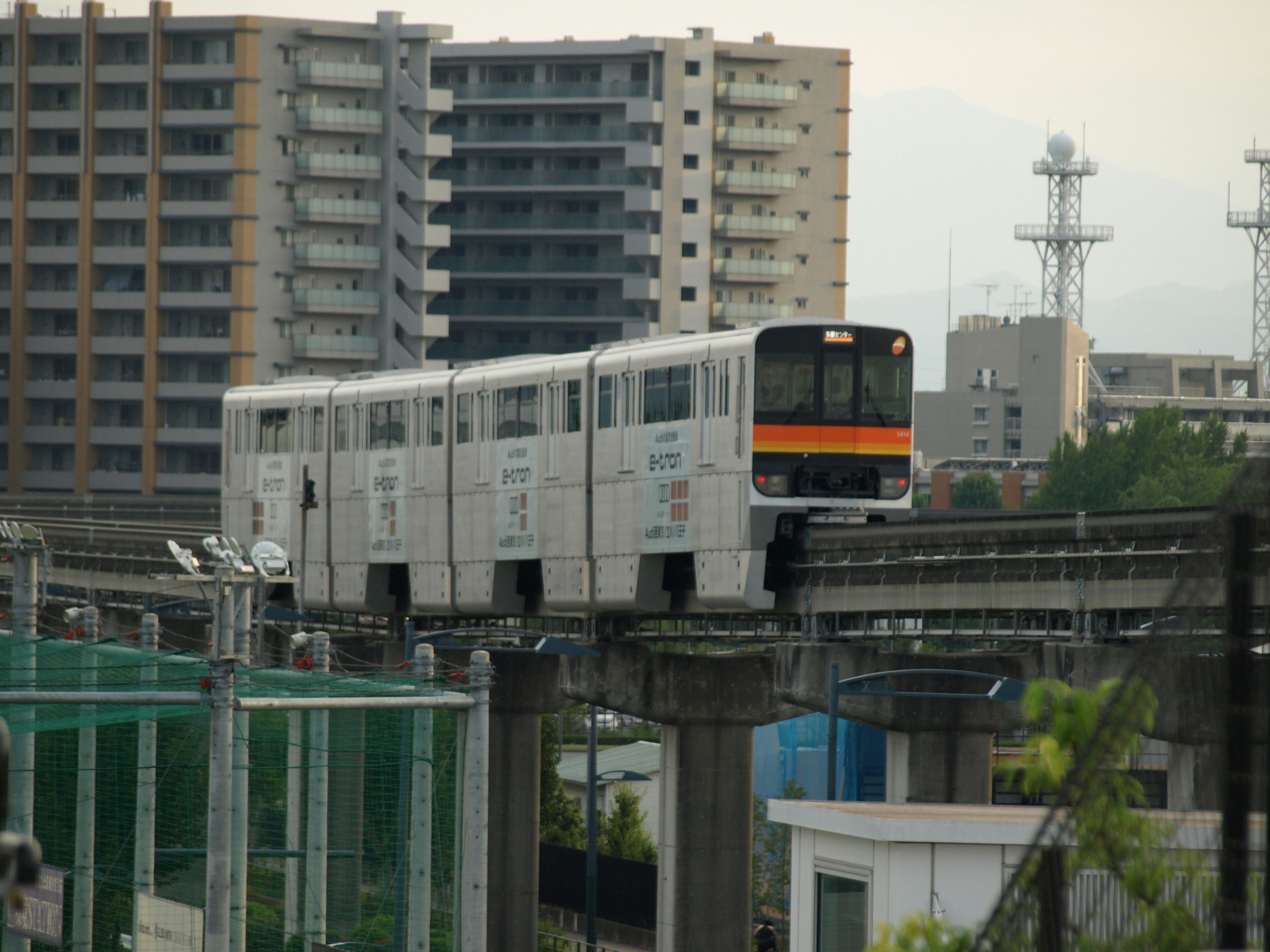 Weißer Monorail-Zug, der auf einer erhöhten Strecke in einer städtischen Umgebung fährt