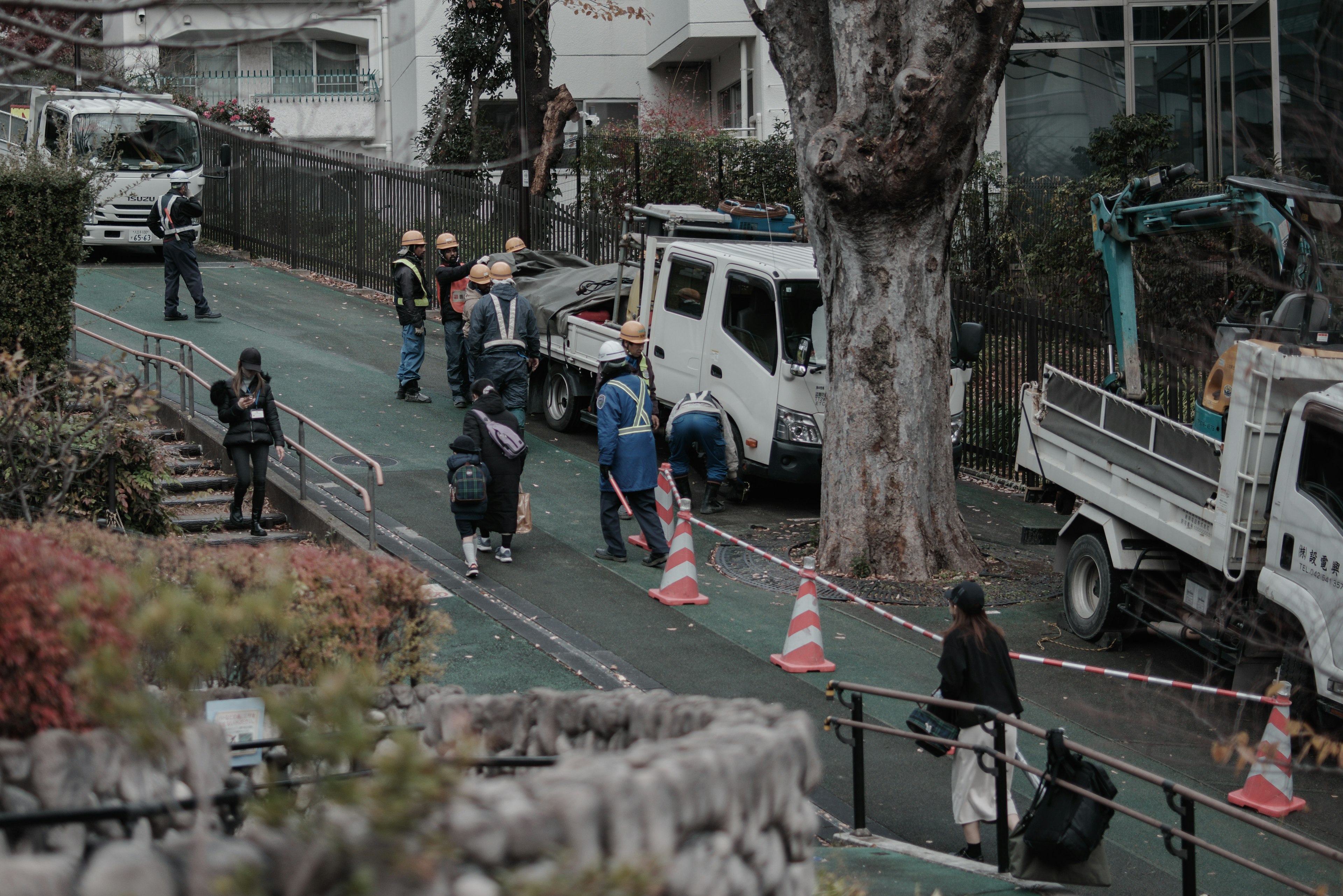 工人在进行道路施工，旁边有卡车和设备