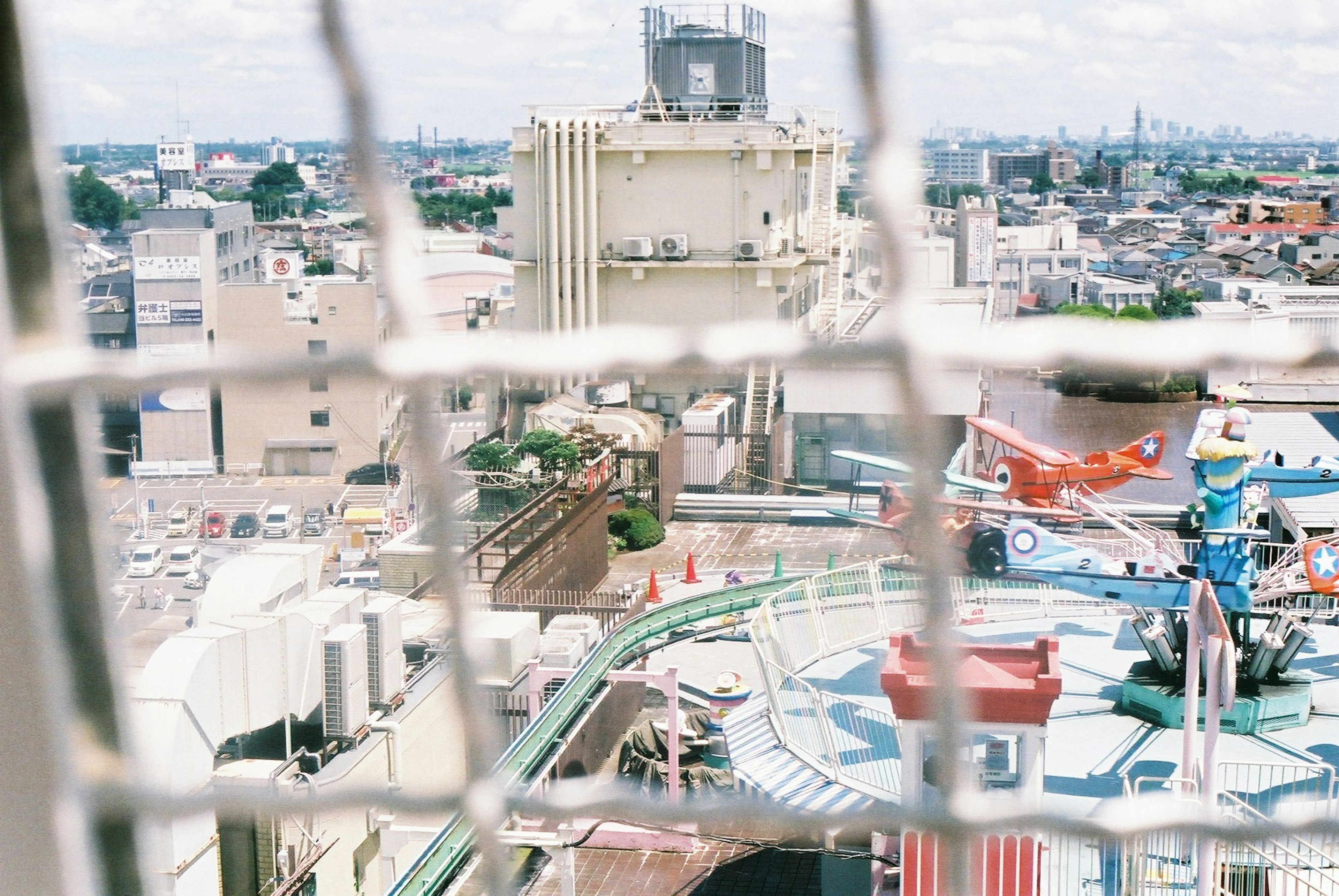 Cityscape view with amusement park attractions seen through a mesh fence