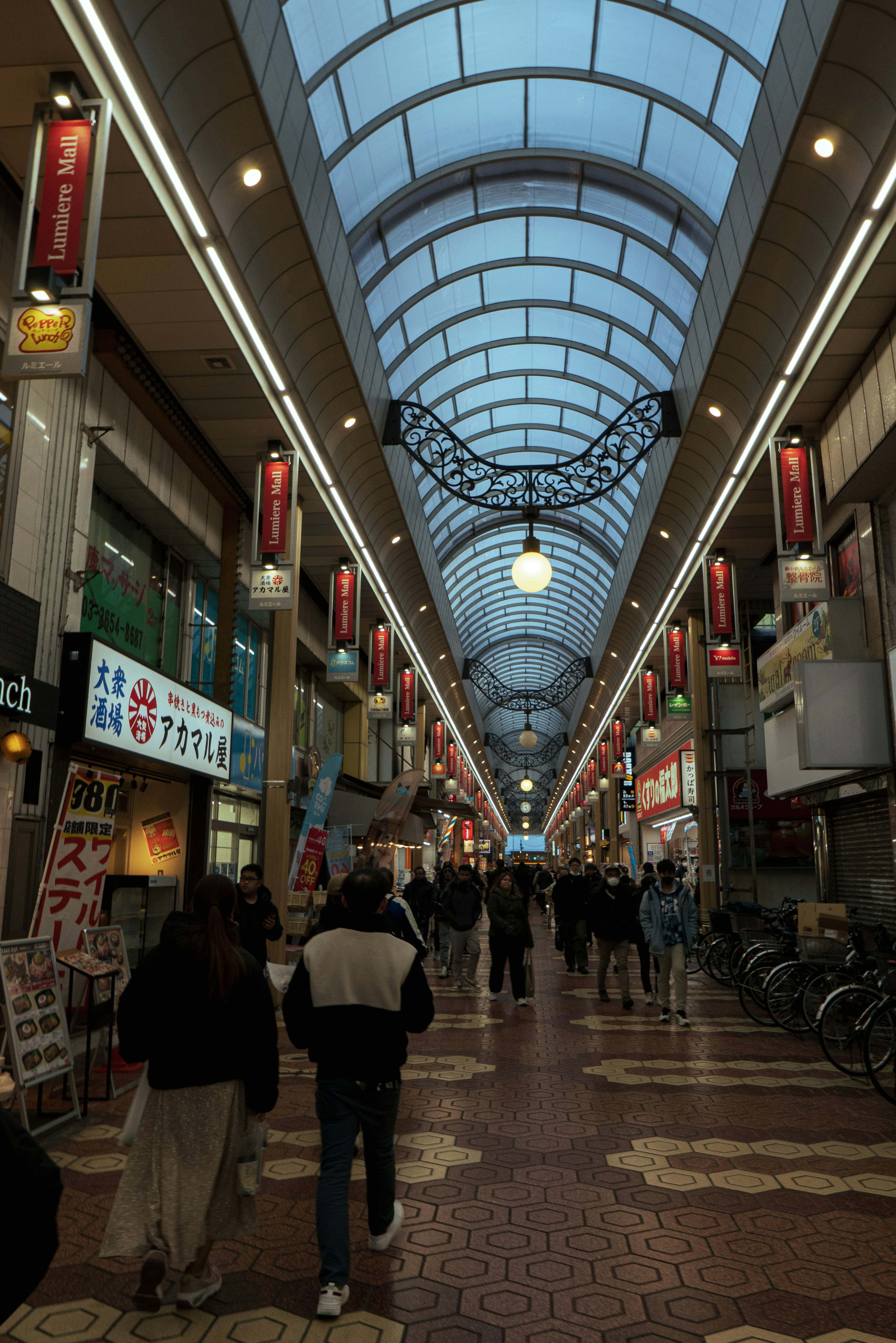 People walking in a shopping arcade under a blue sky