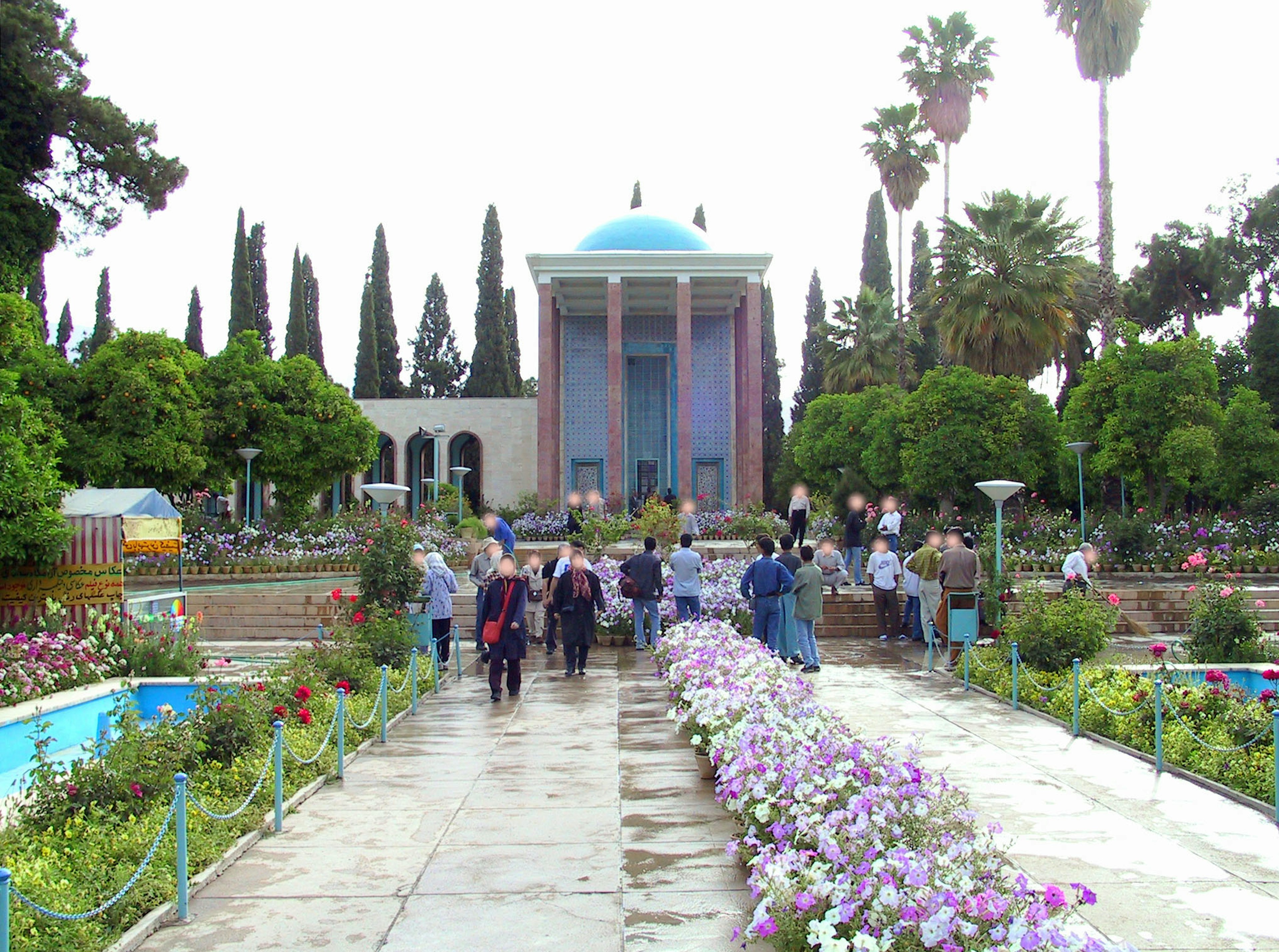 Visitors walking through a beautiful garden with a blue domed building in the center