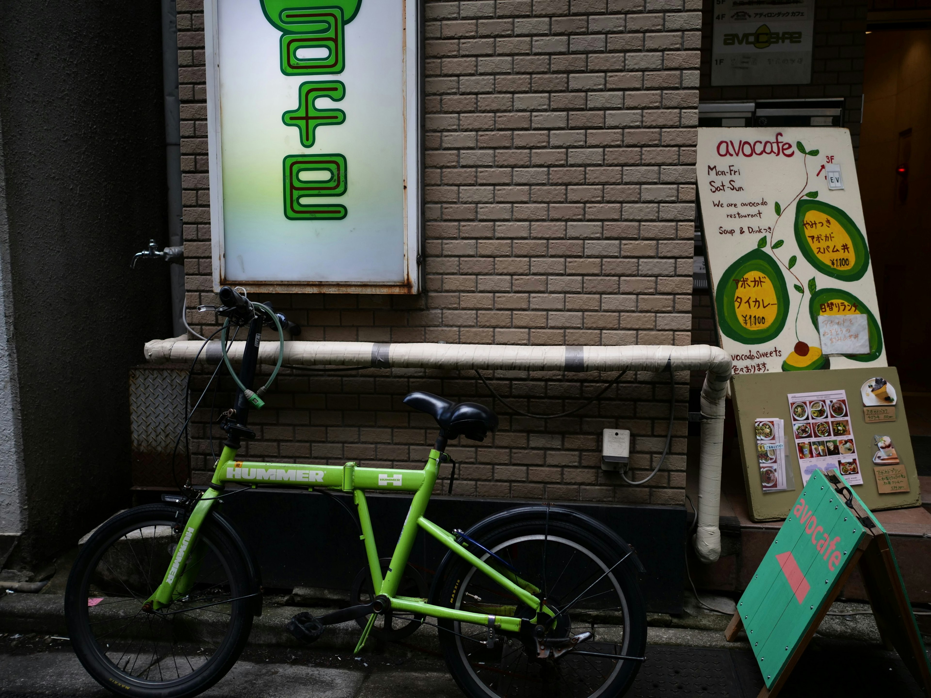 緑の自転車とカフェの看板がある街の風景