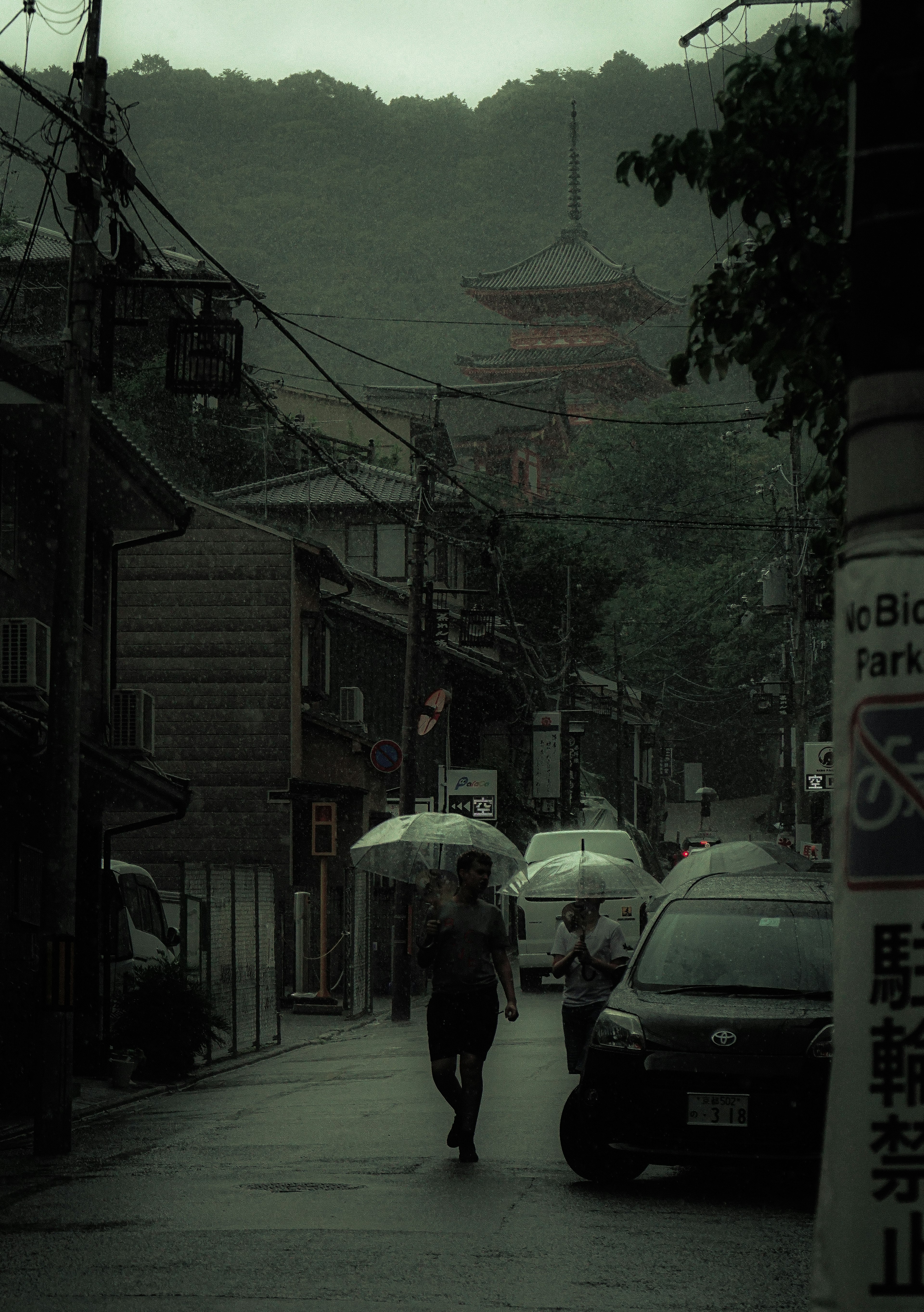 霧の中を歩く傘を持った人と古い建物が見える風景