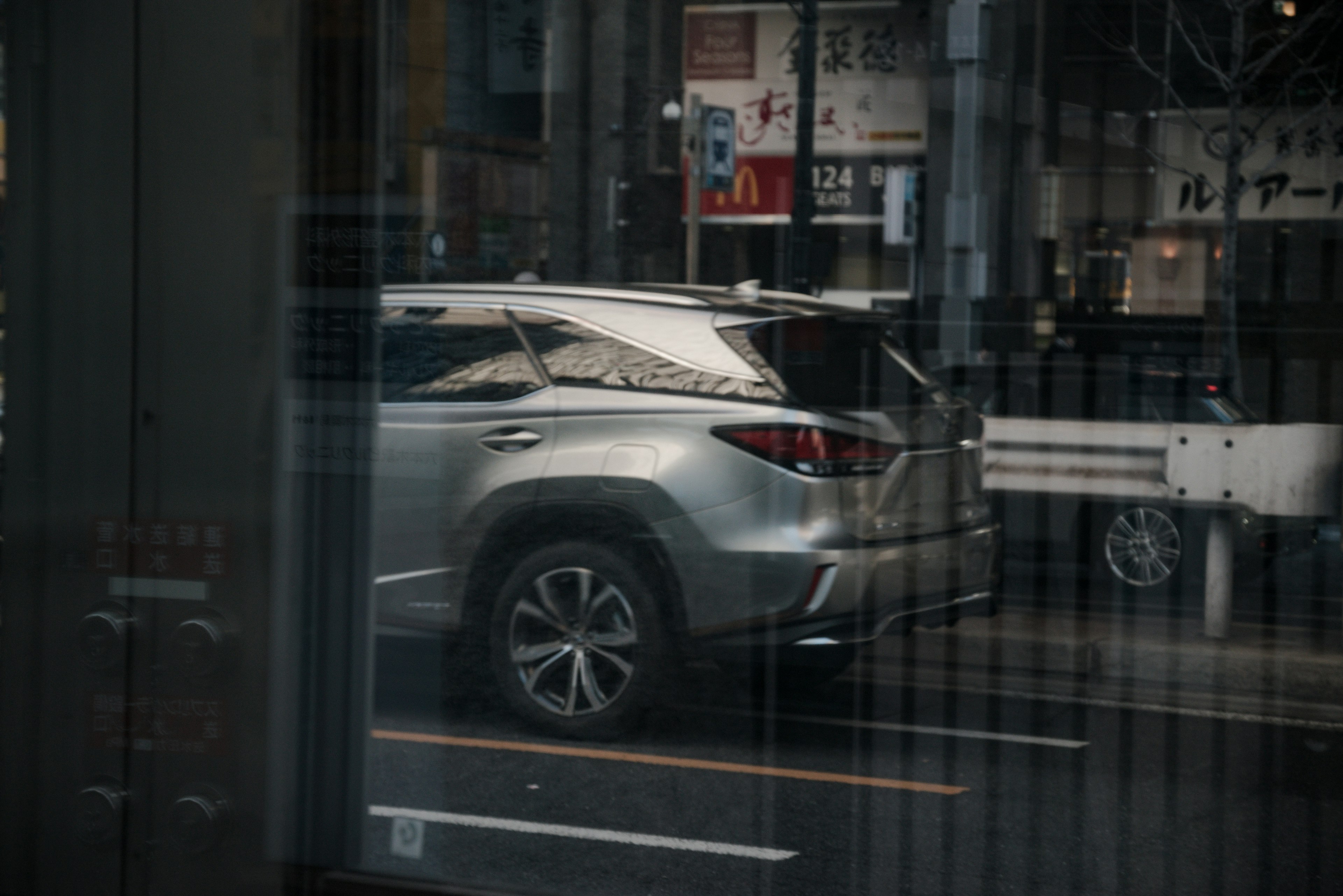 SUV plateado visto a través de una ventana con fondo urbano