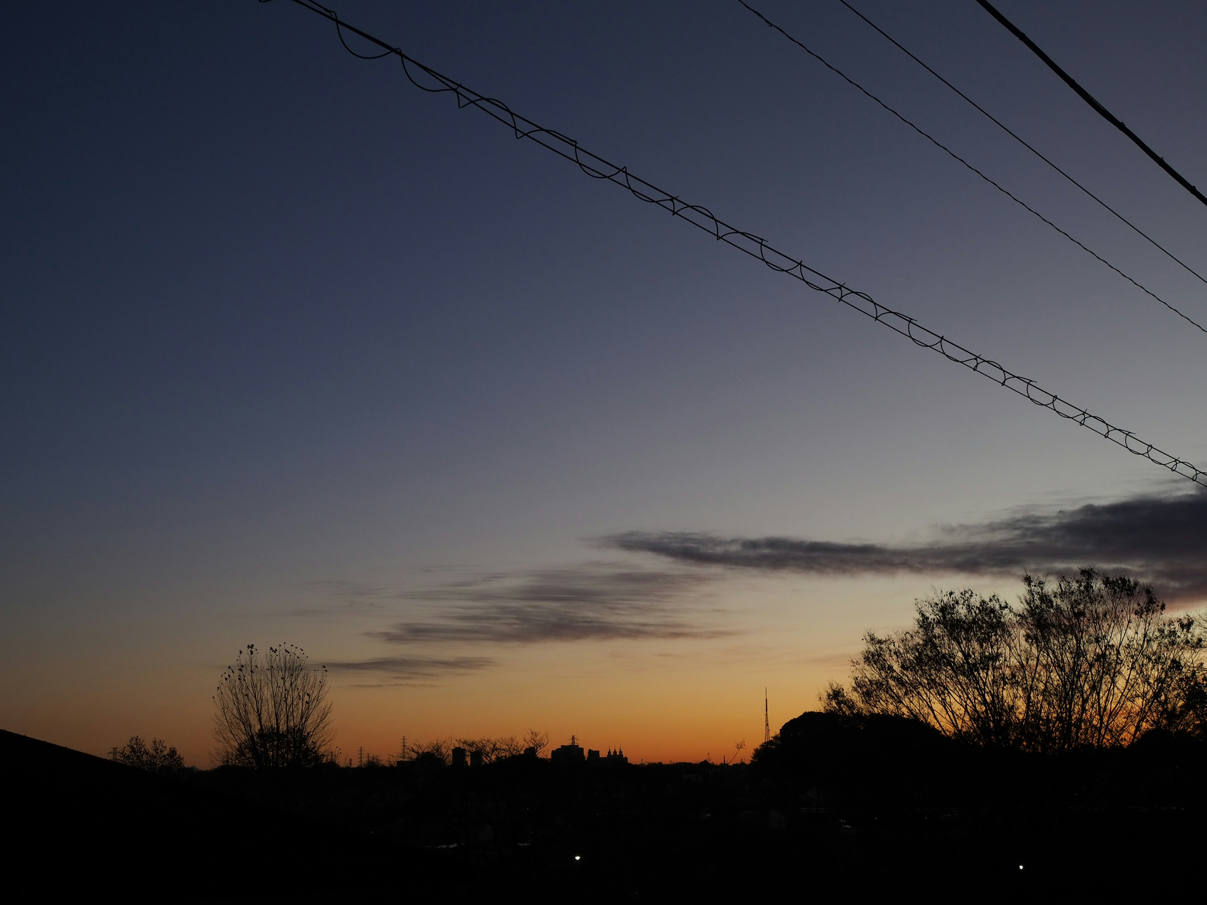 夕焼けの空に電線が横たわる風景