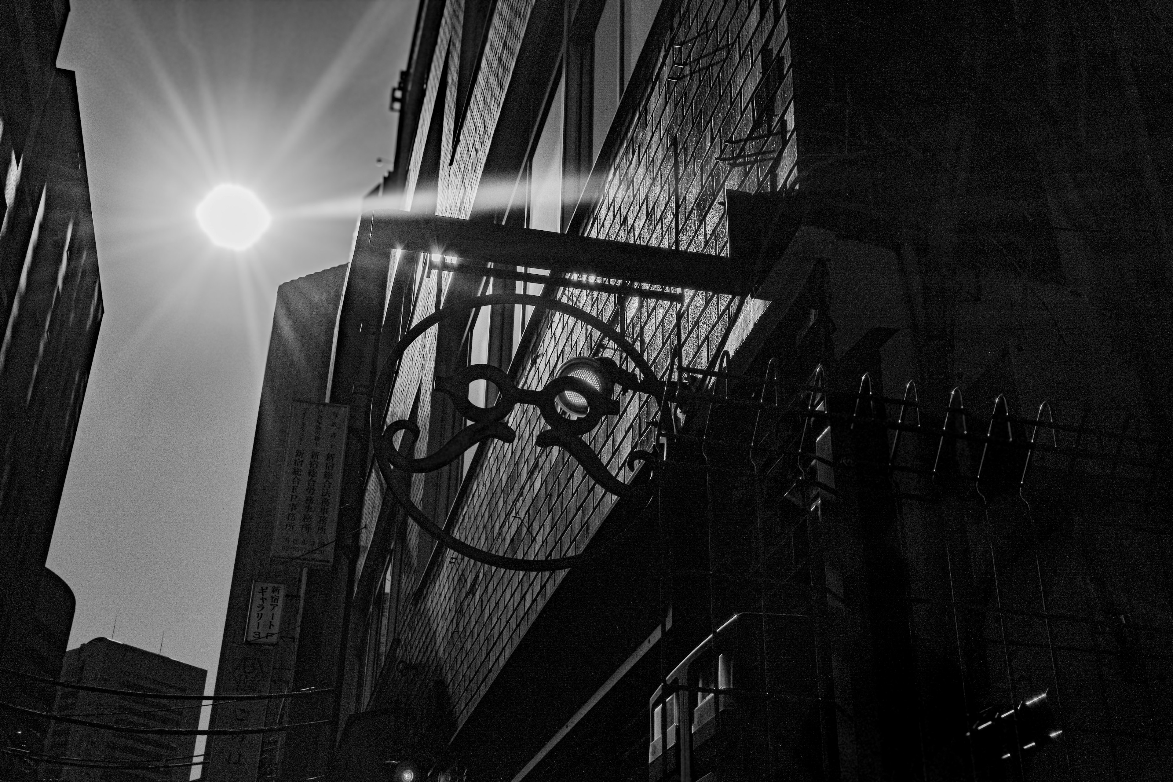 Silhouette of a black building with a sign in a narrow street illuminated by sunlight