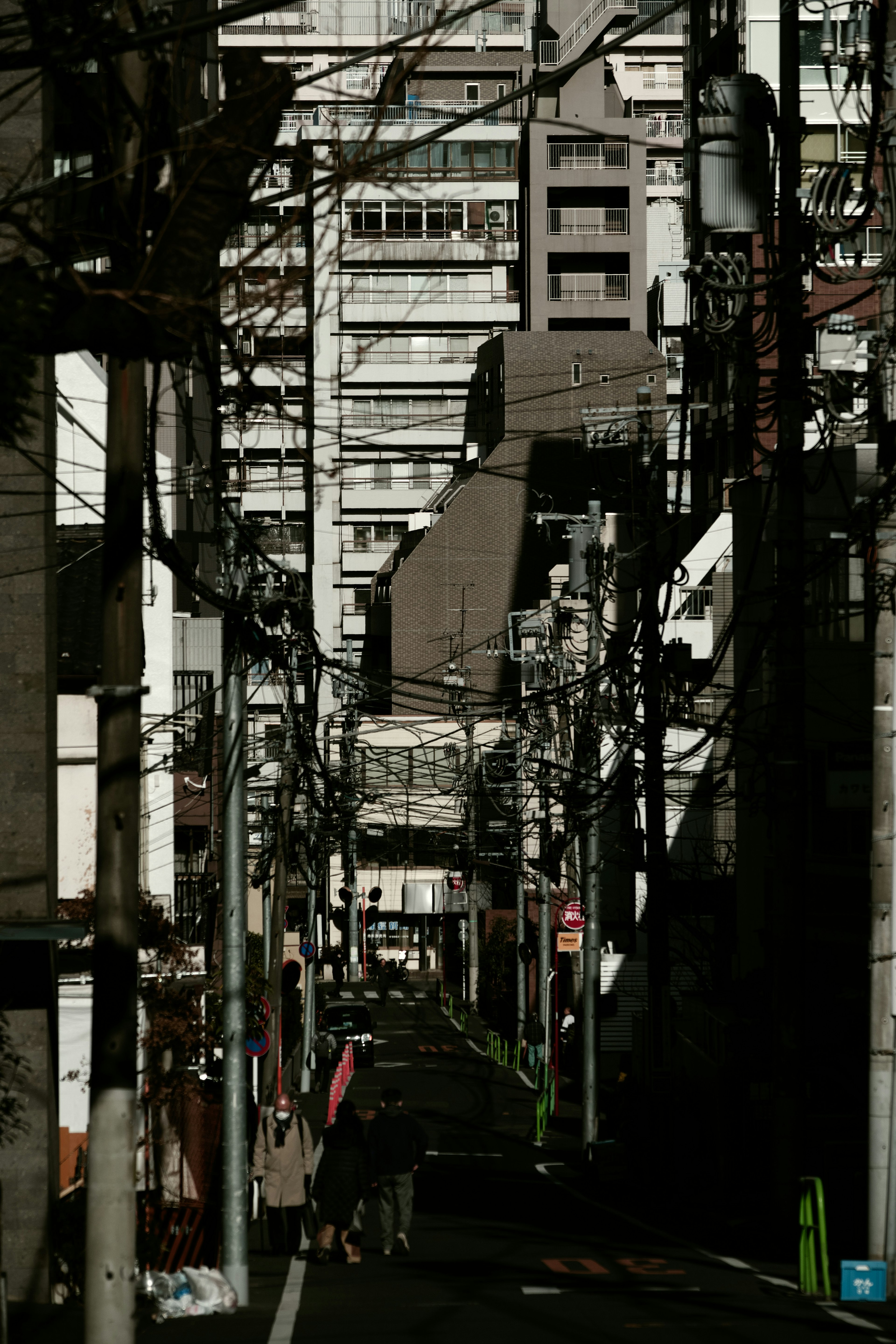 Narrow alley lined with tall buildings and power lines