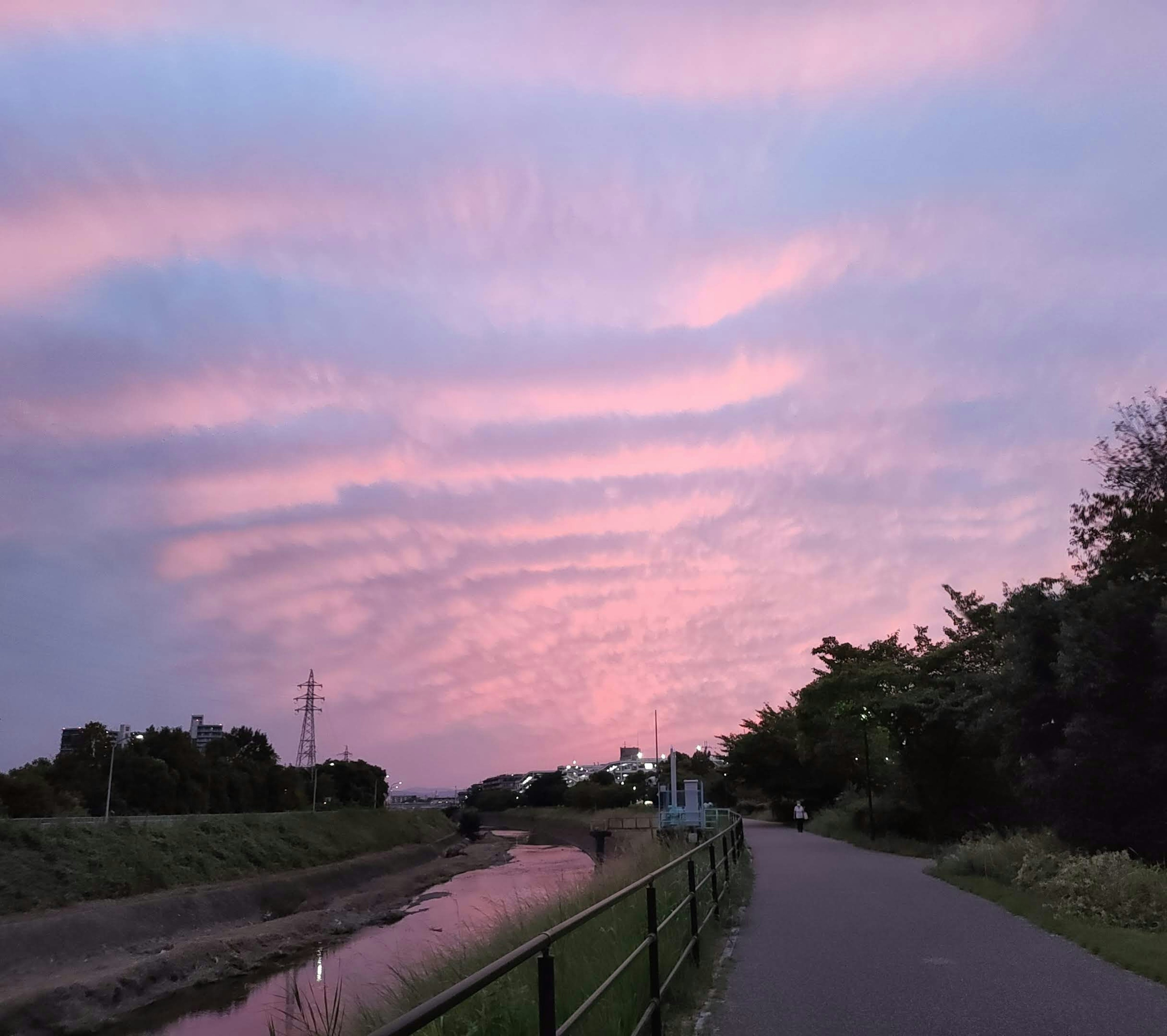 Cielo de atardecer con nubes sobre un camino junto al río