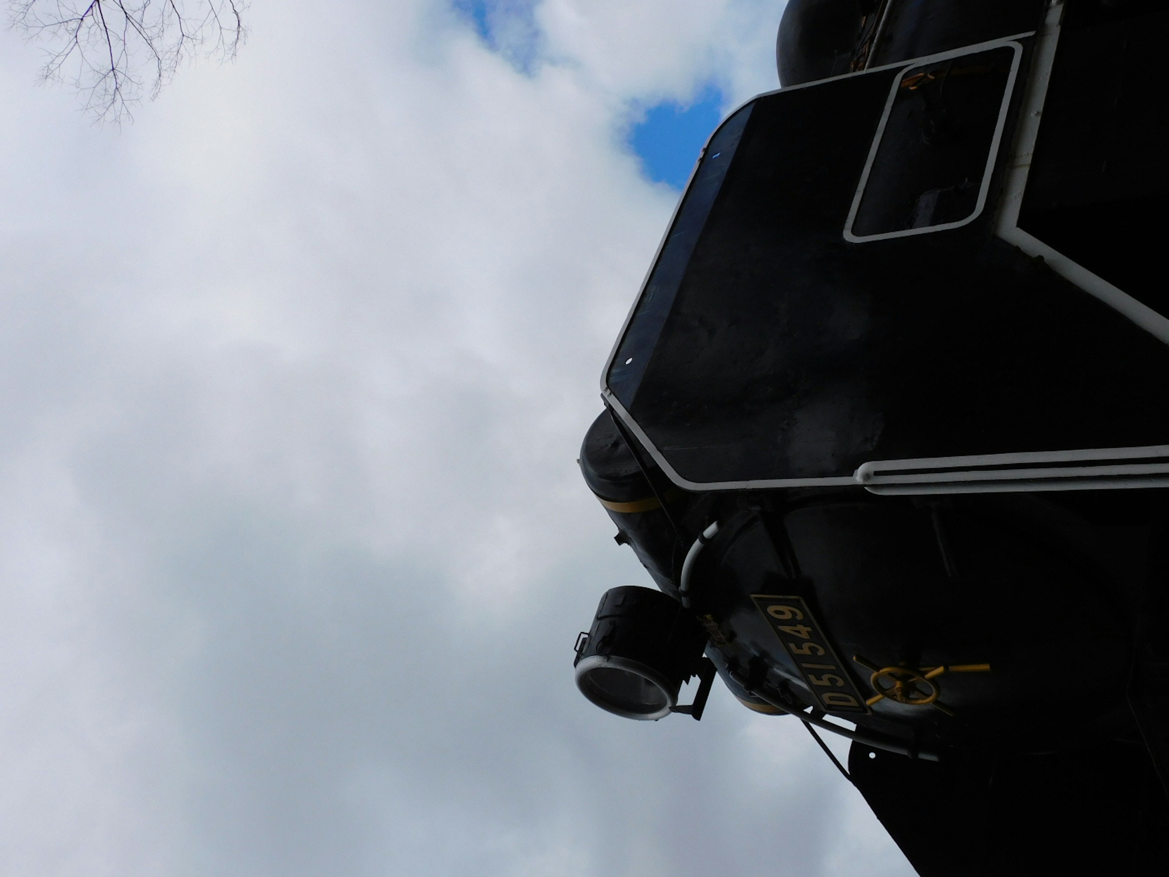 Part of a black train with clouds in a blue sky