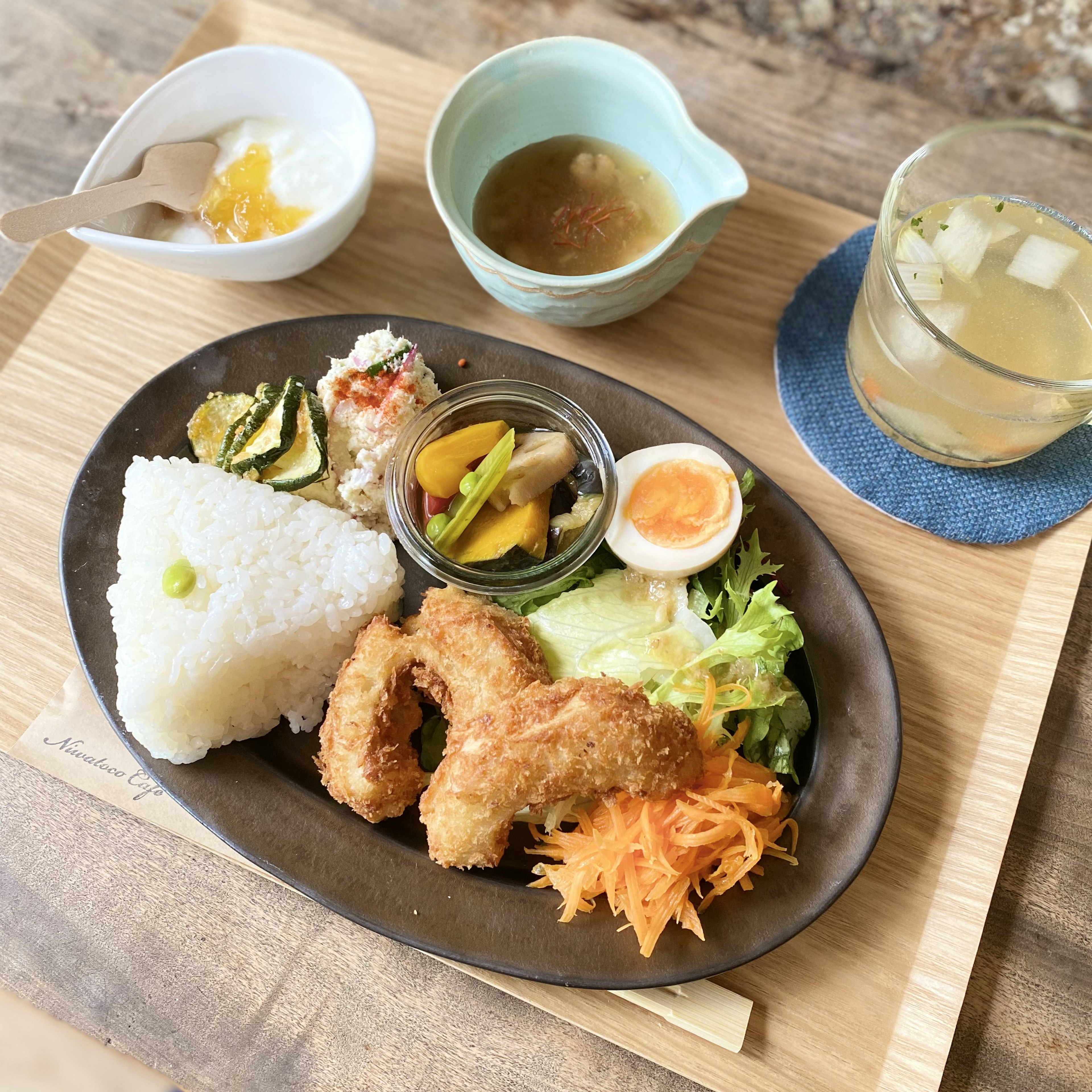 A delicious Japanese meal plate featuring fried chicken, salad, rice, egg, and pickles