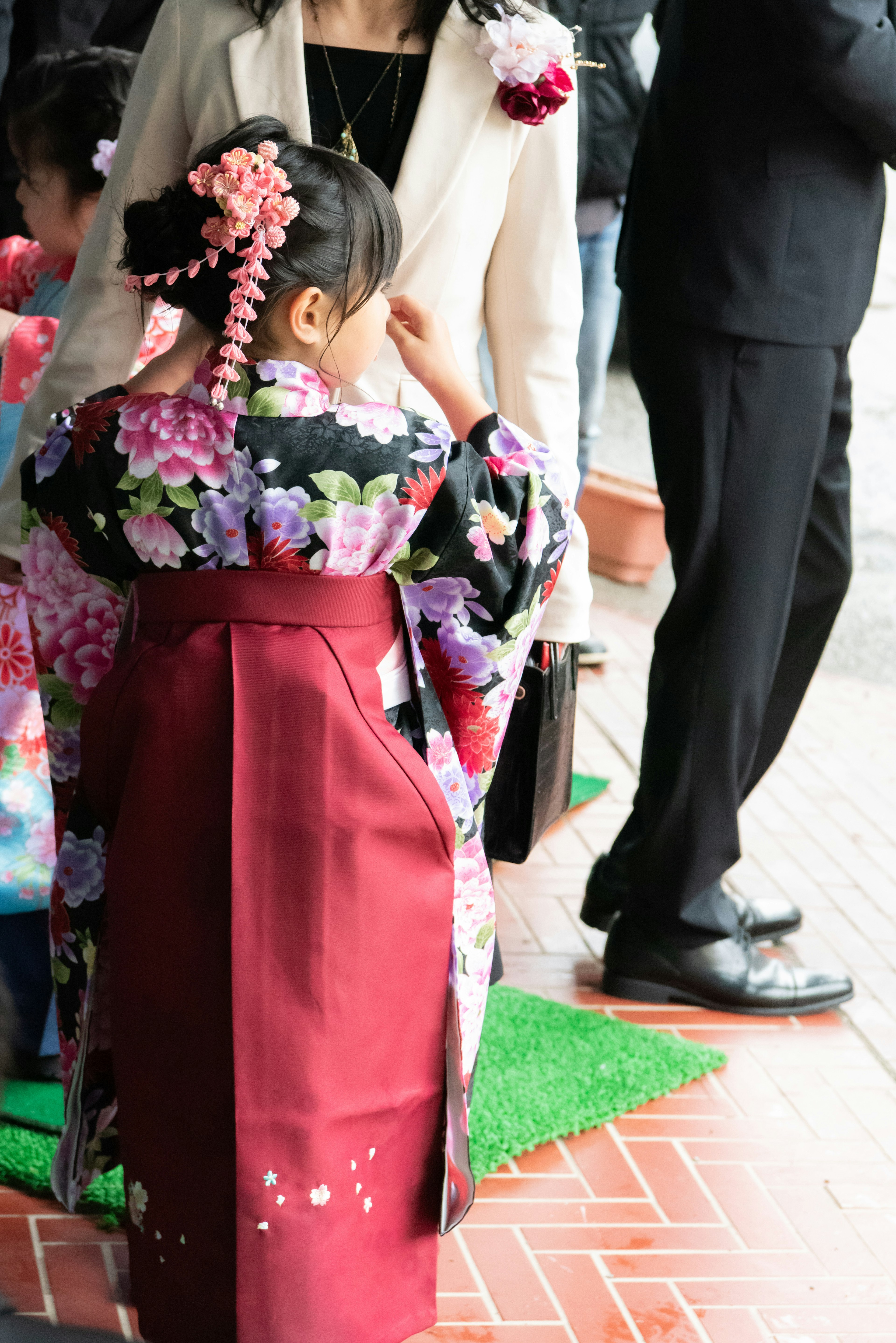 A young girl wearing a traditional kimono with floral patterns seen from behind