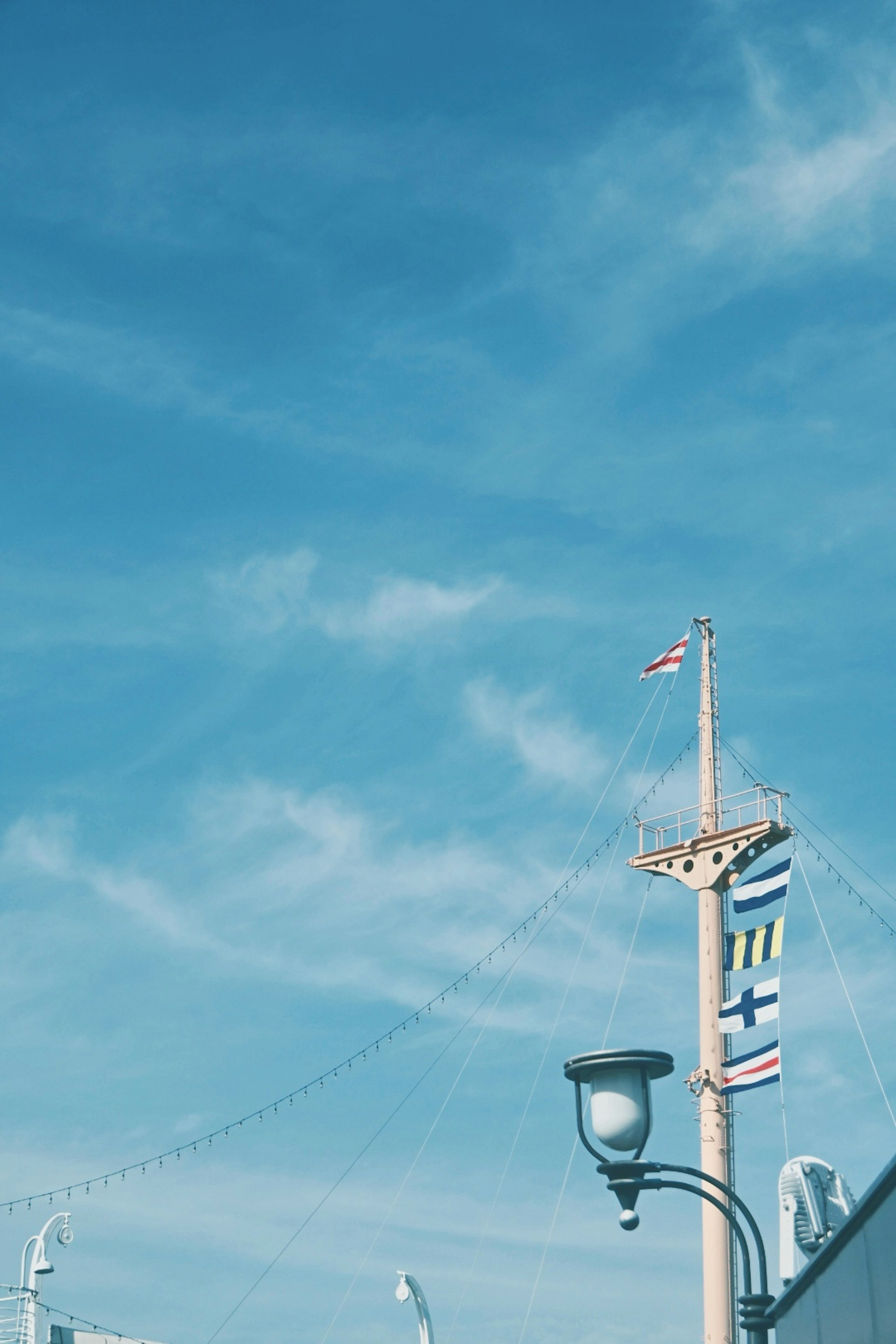 Flaggenmast mit verschiedenen Fahnen unter blauem Himmel