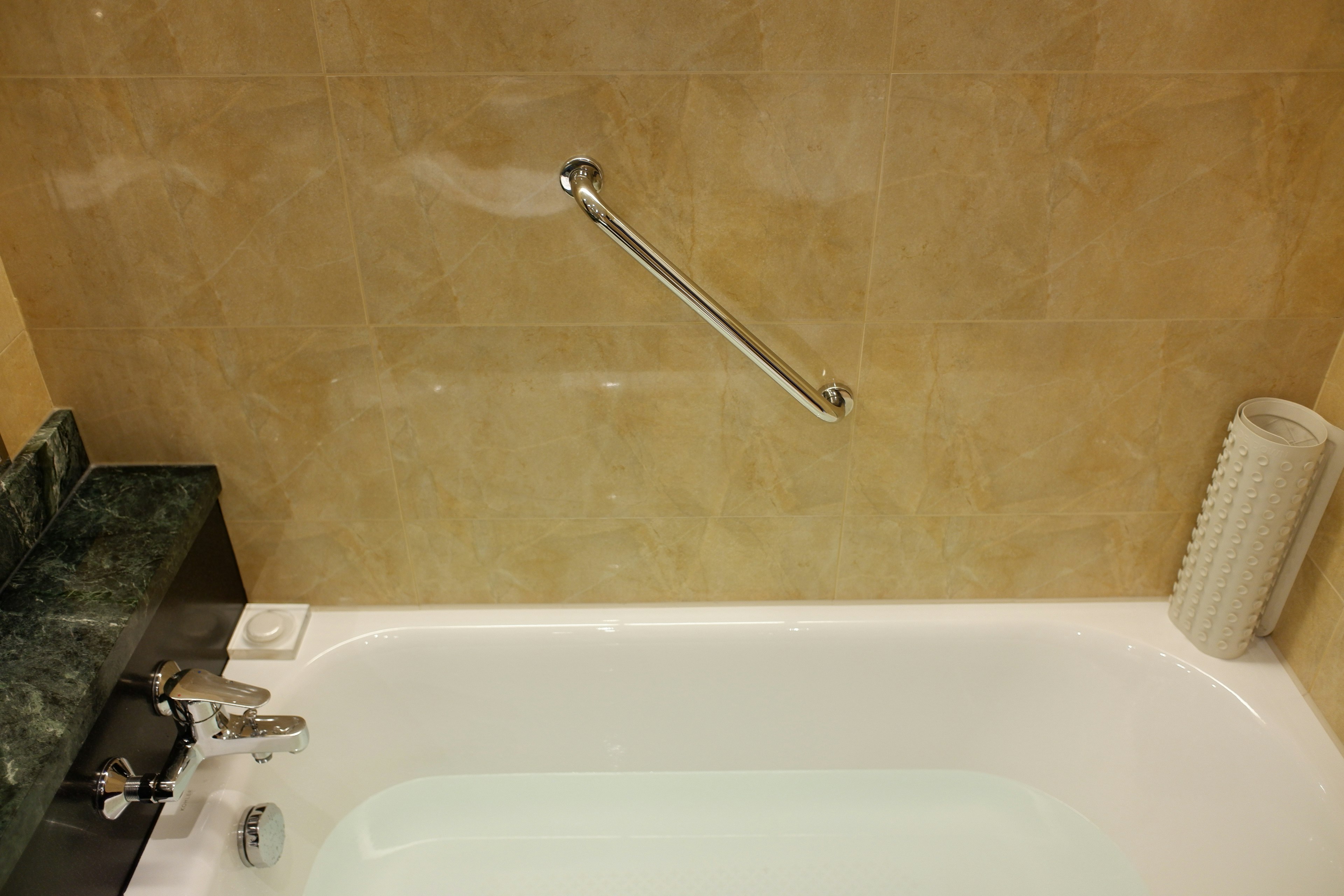 Simple bathroom featuring a bathtub and tiled wall