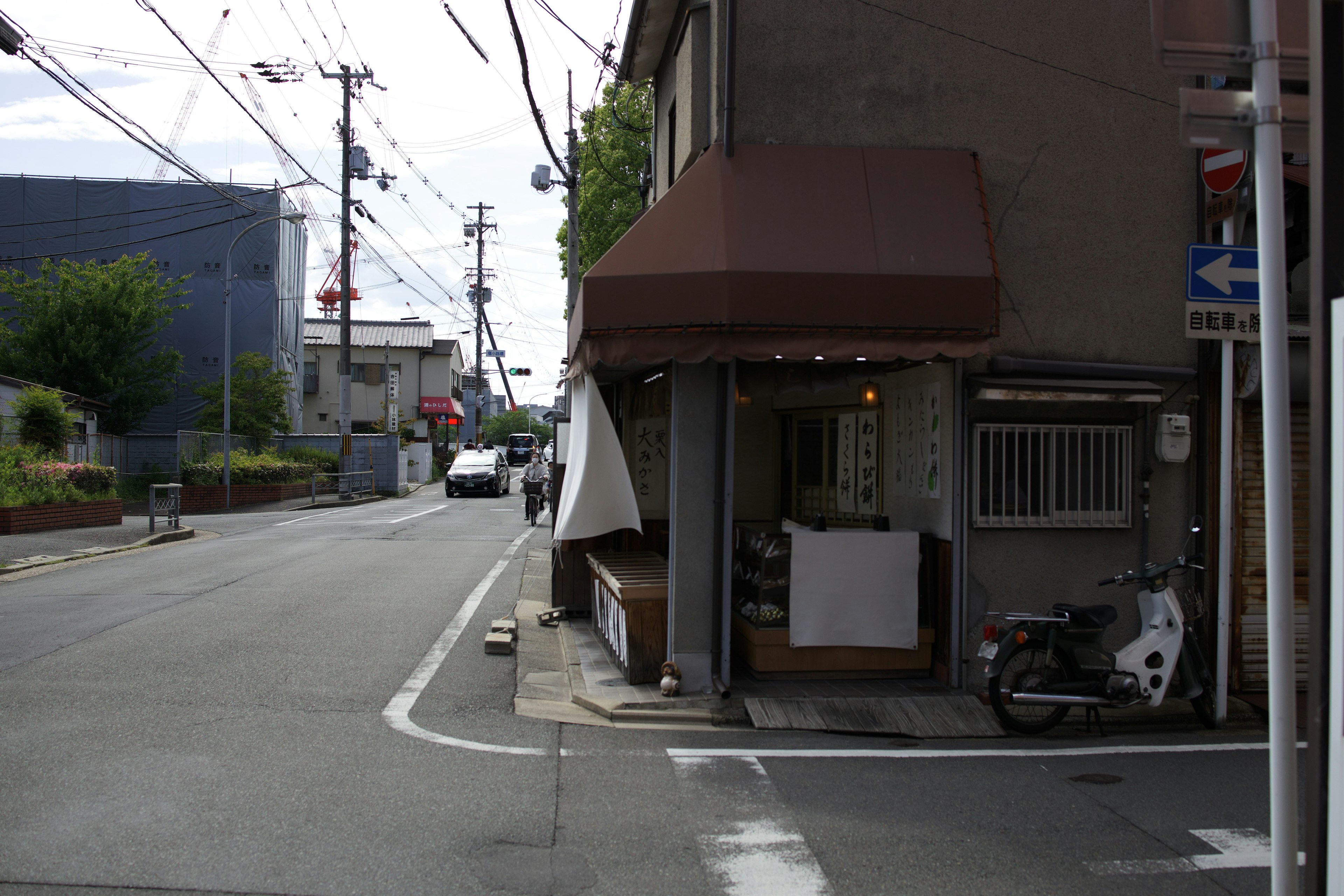 街角の小さな店舗と白いバイクが見える風景