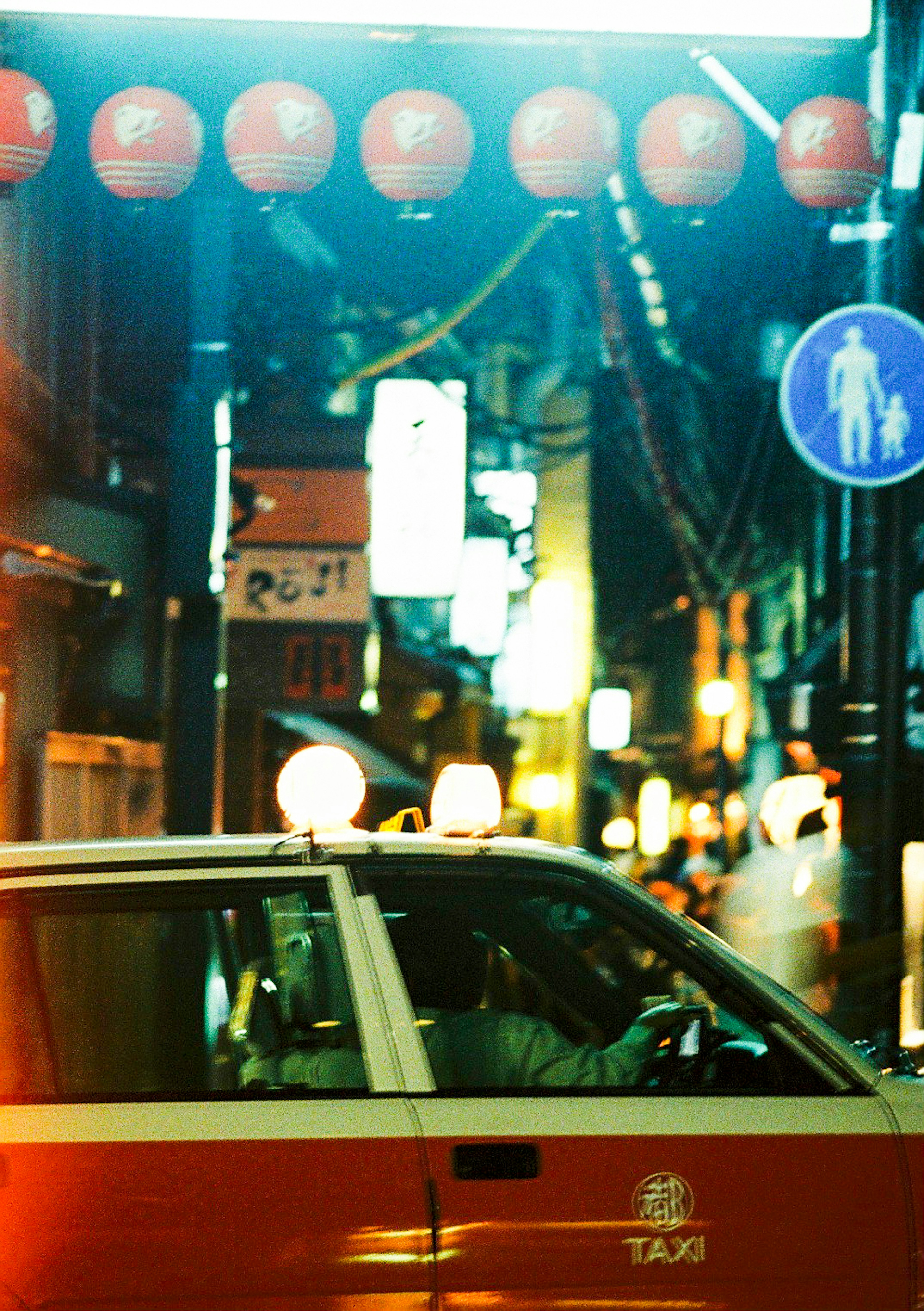 A red taxi on a street with lanterns at night