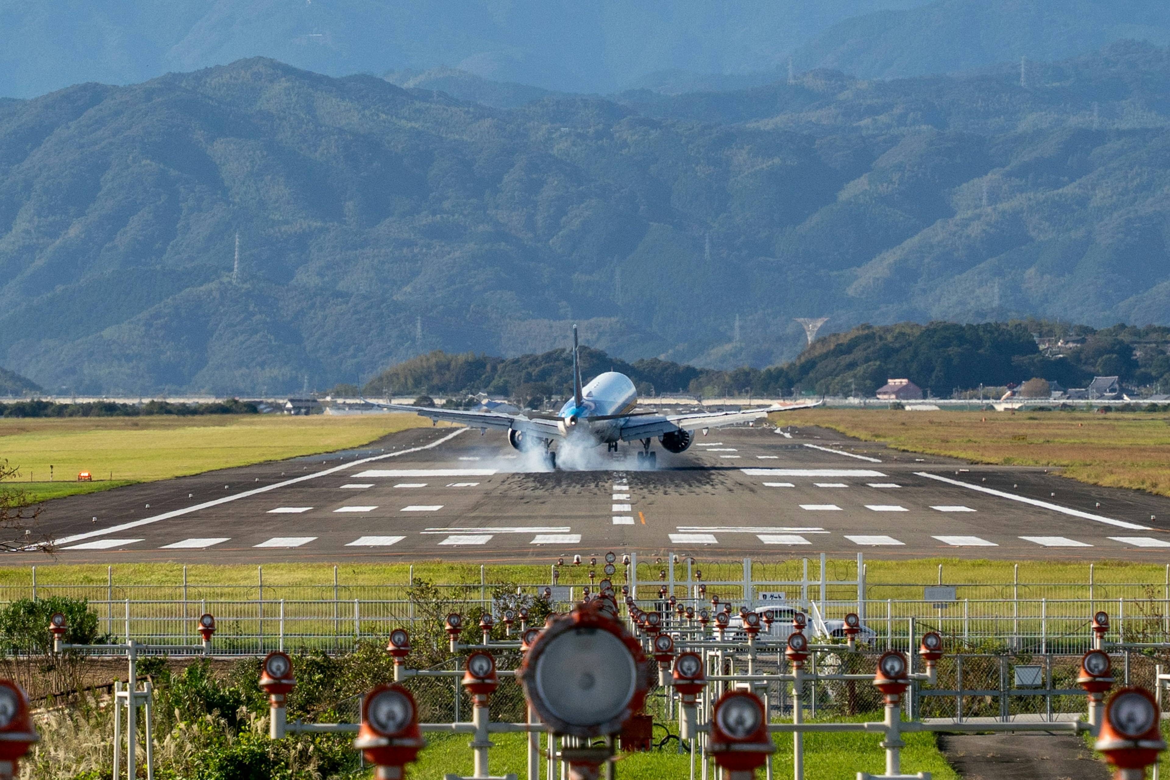 Aereo che atterra sulla pista con montagne sullo sfondo