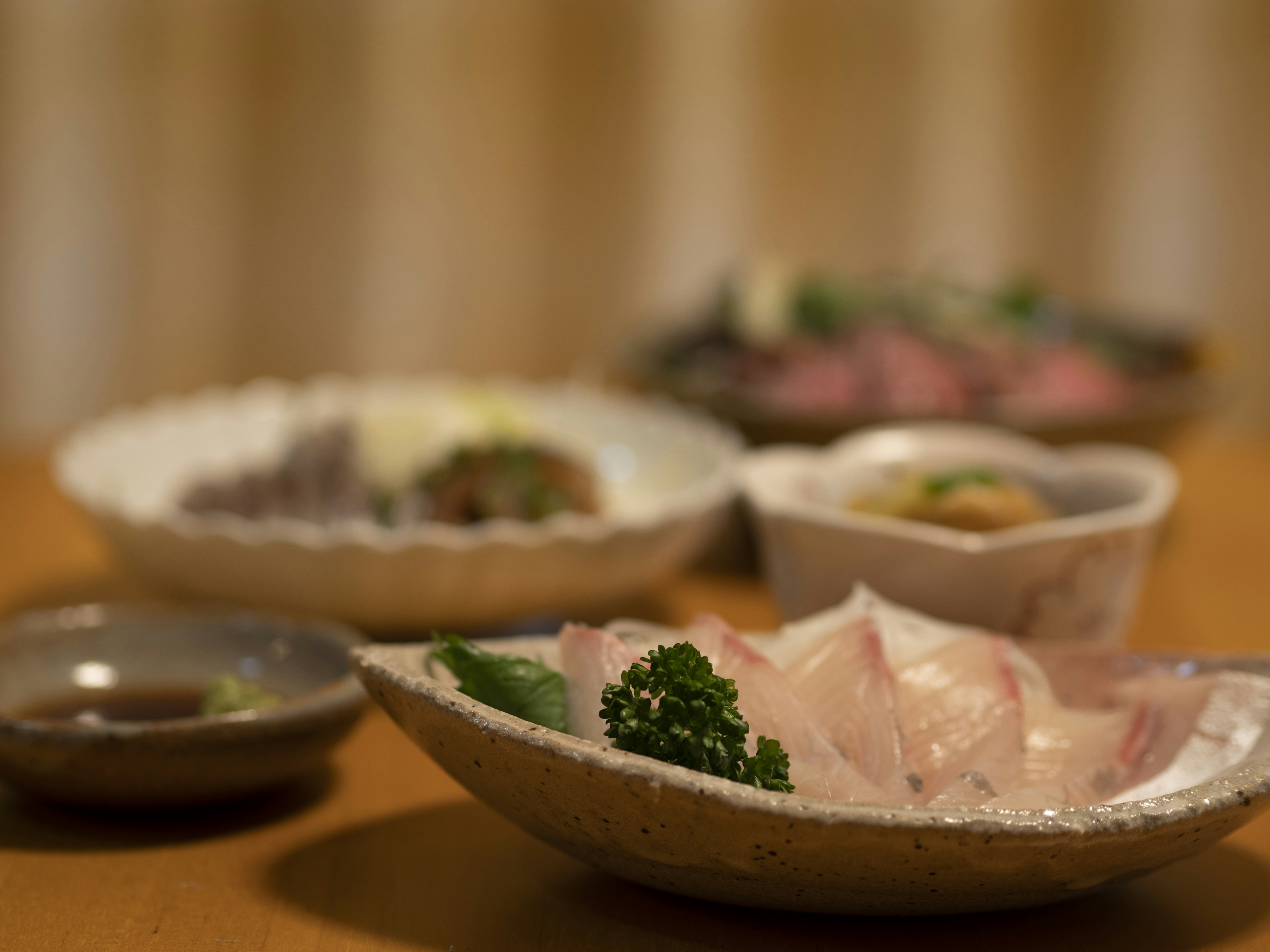 Una escena de mesa bellamente dispuesta con varios platos de cocina japonesa que incluyen sashimi y guarniciones