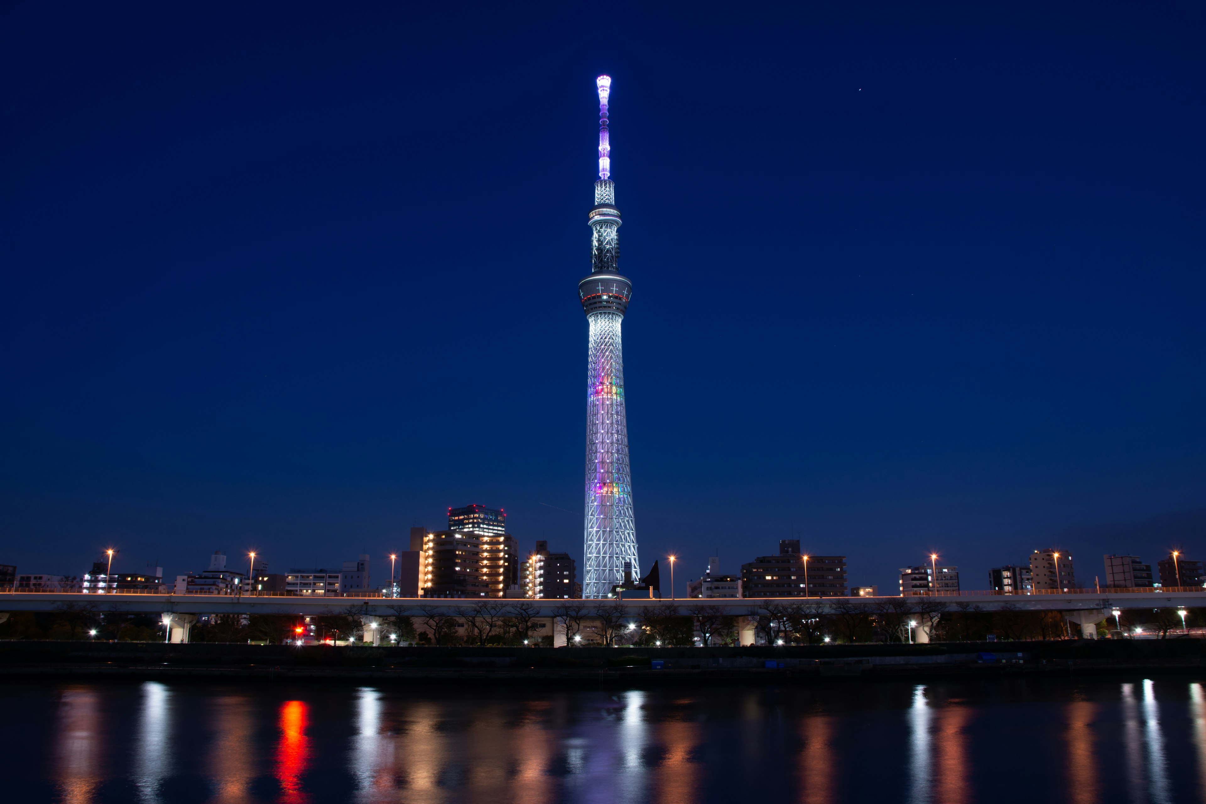 Tokyo Skytree iluminado por la noche con reflejos en el río