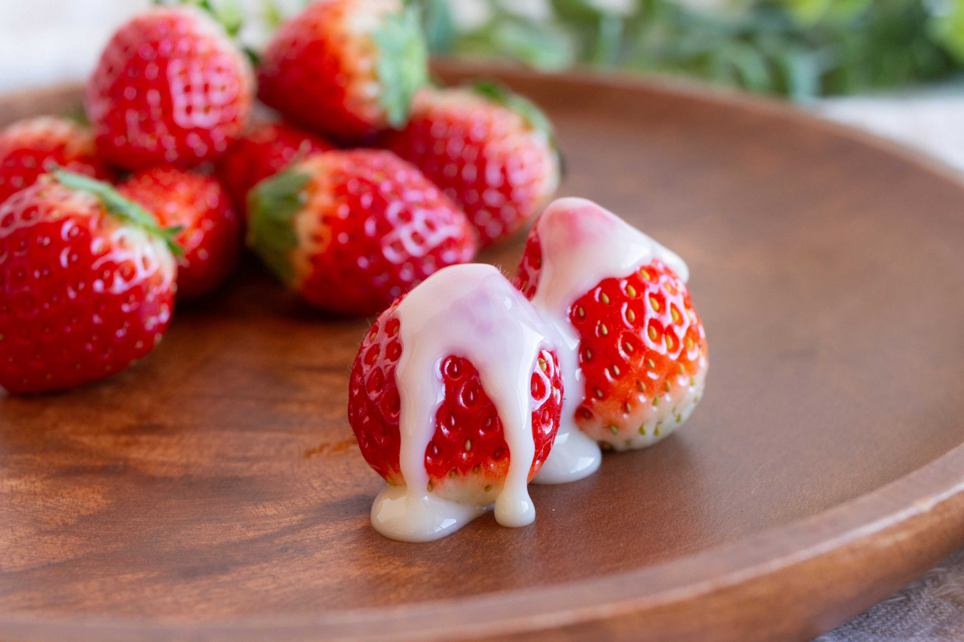 Fresh strawberries drizzled with creamy sauce on a wooden plate