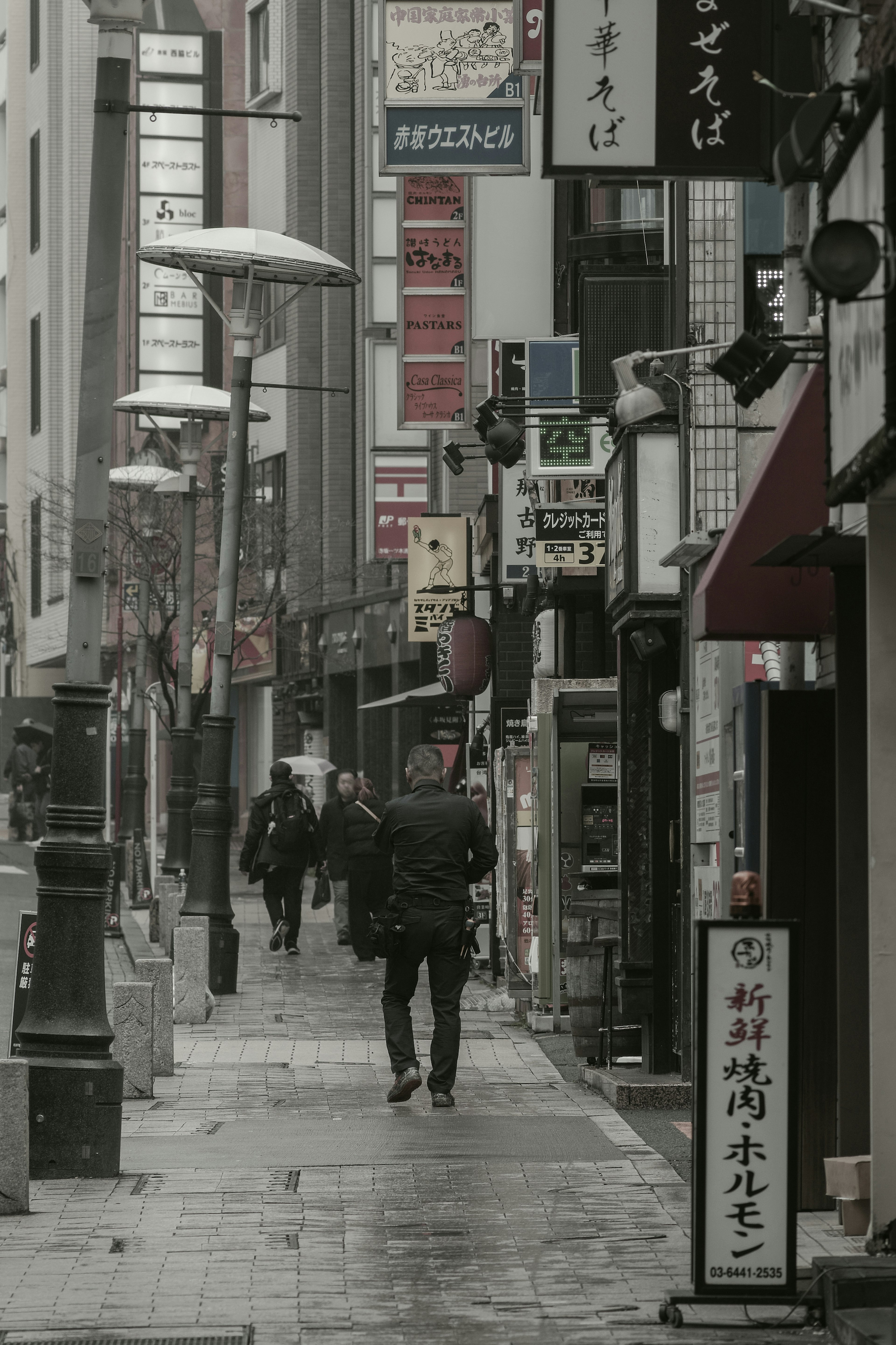 雨中在狭窄街道上行走的人和招牌