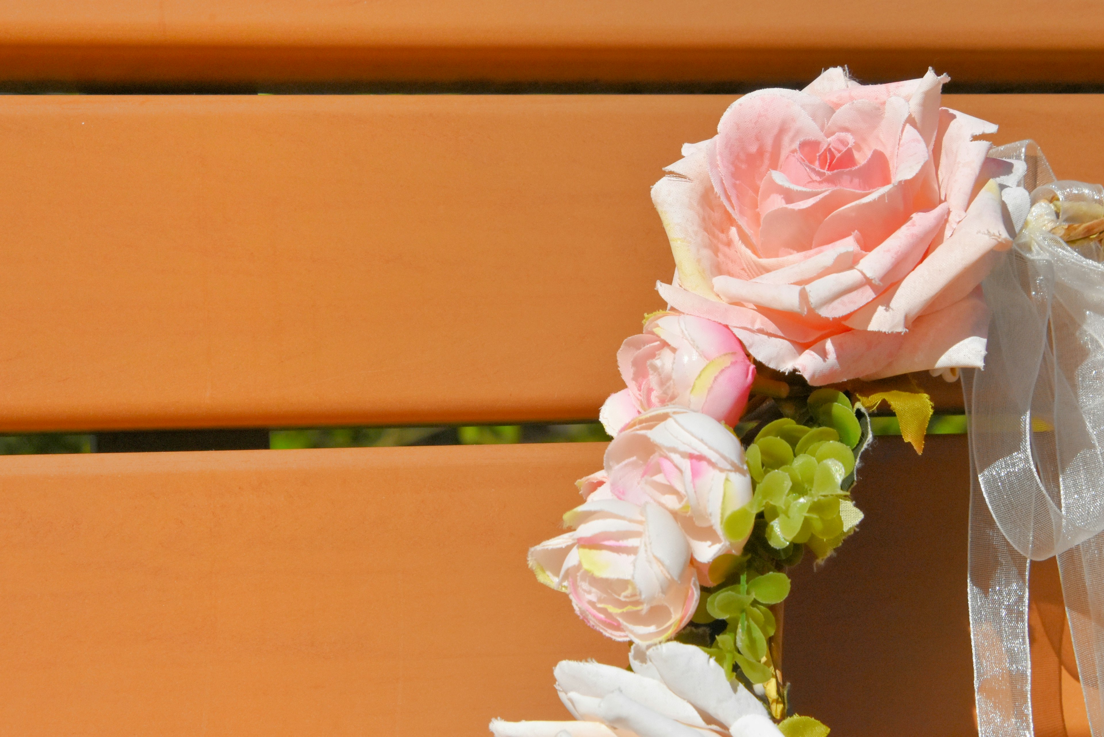 Floral crown made of pink roses and white flowers on an orange bench