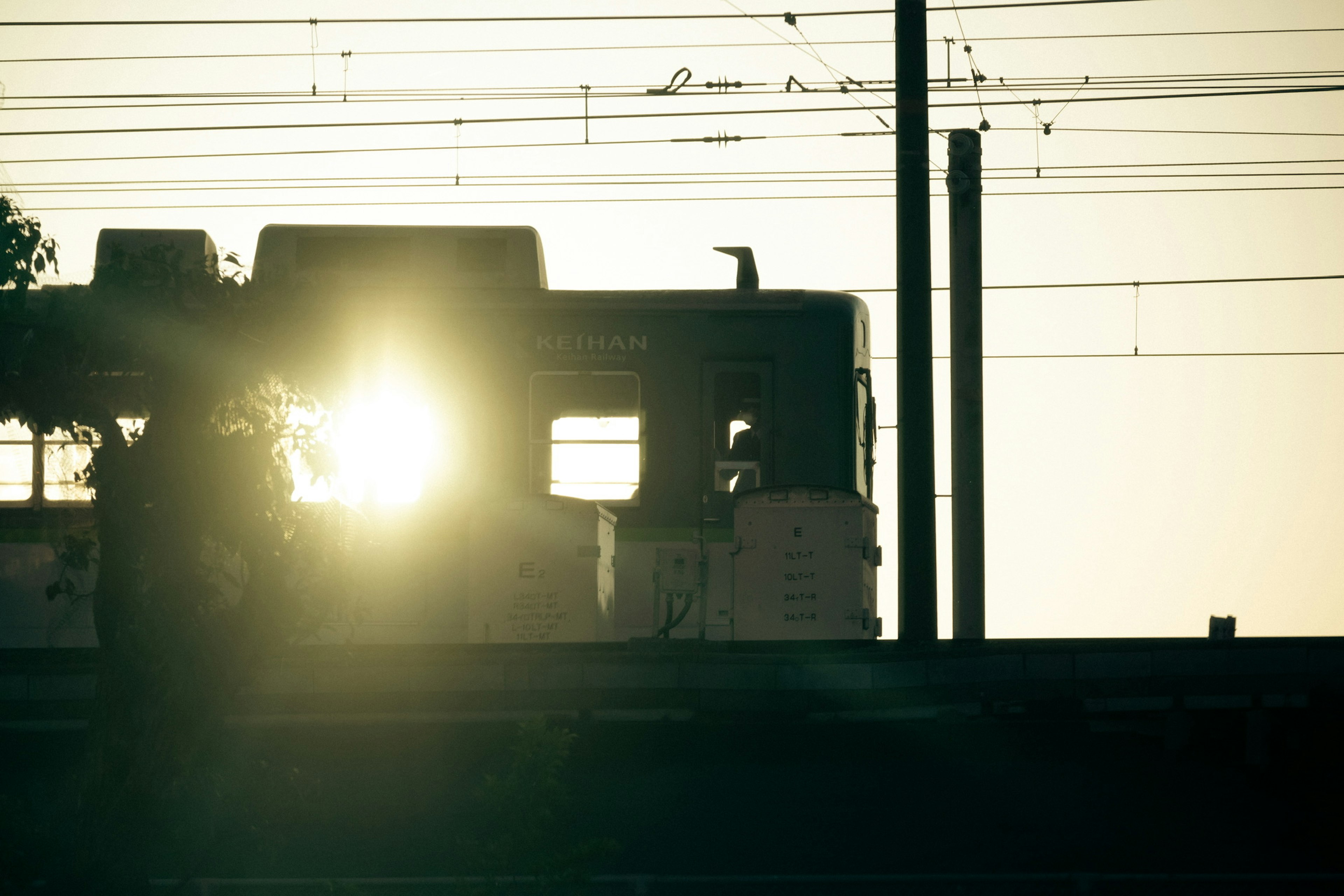 夕日を背にした列車のシルエットと電線