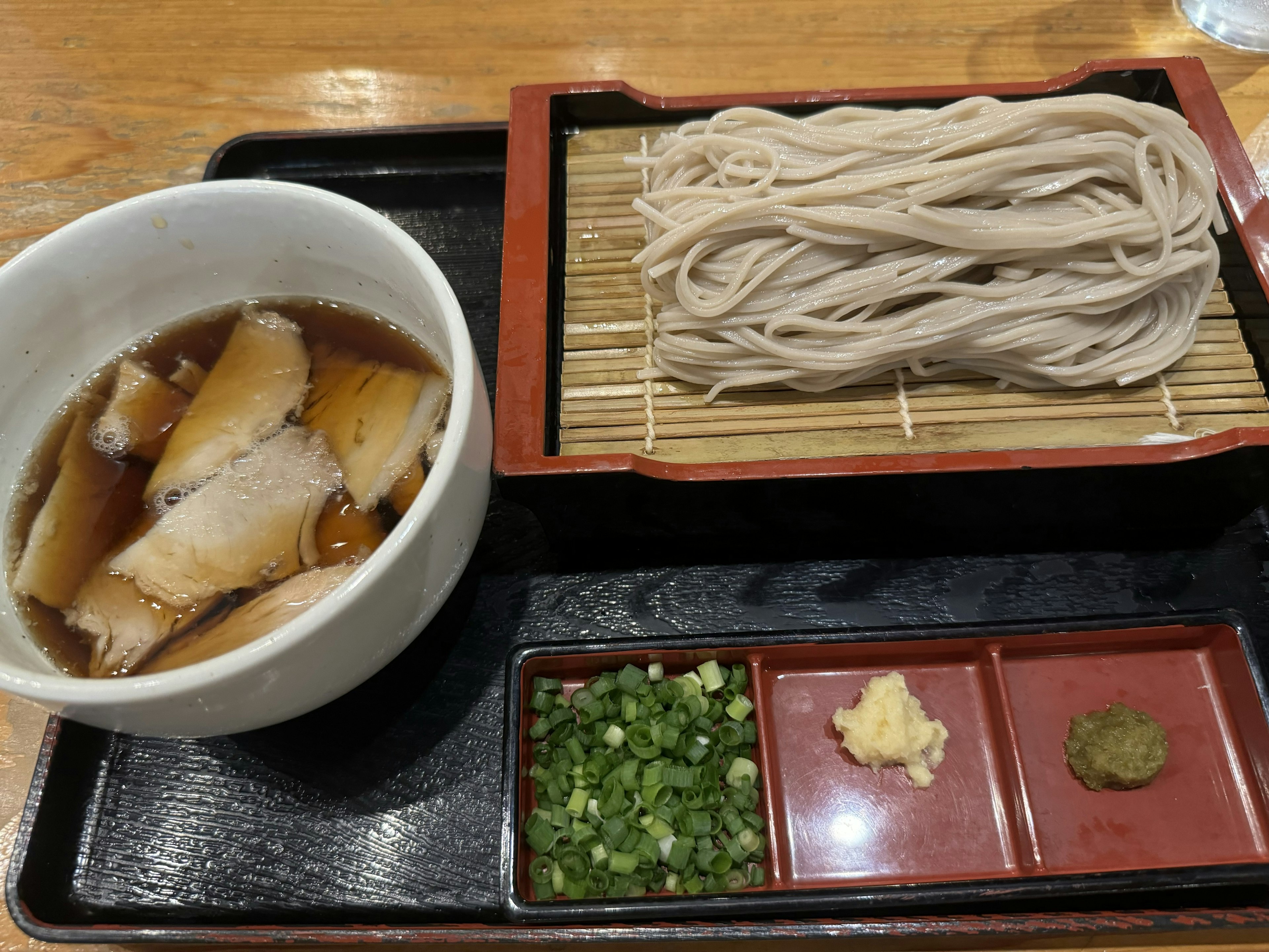 Teller mit Soba-Nudeln, serviert mit Dip-Sauce und Scheiben von Chashu sowie Gewürzen