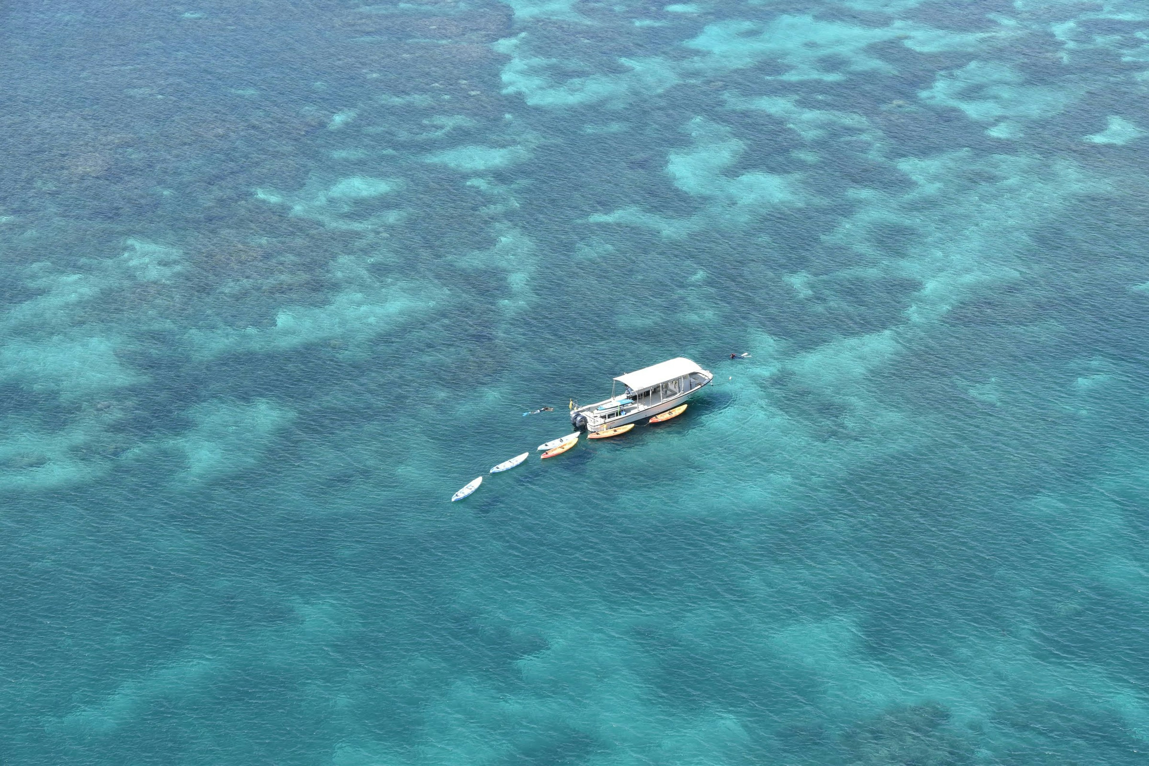 Barco flotando en un océano azul con arrecifes de coral