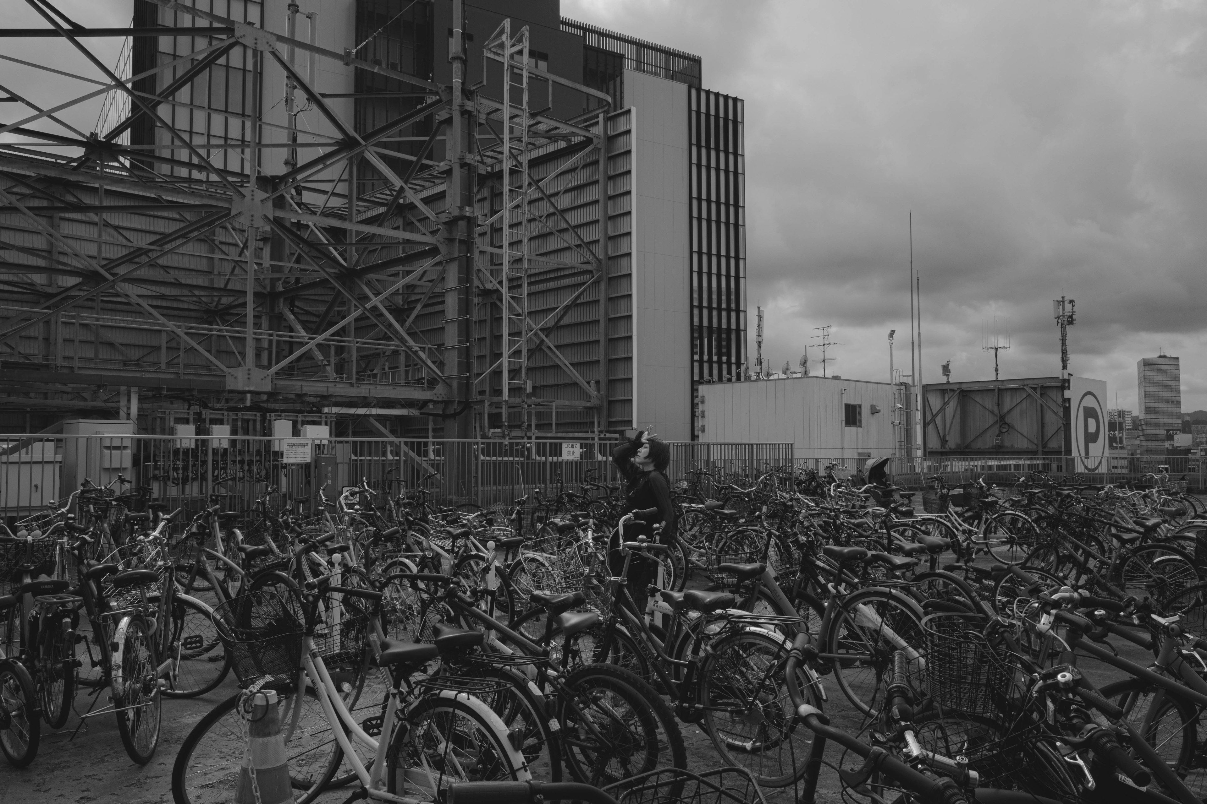 A crowded bicycle parking area with modern buildings in the background