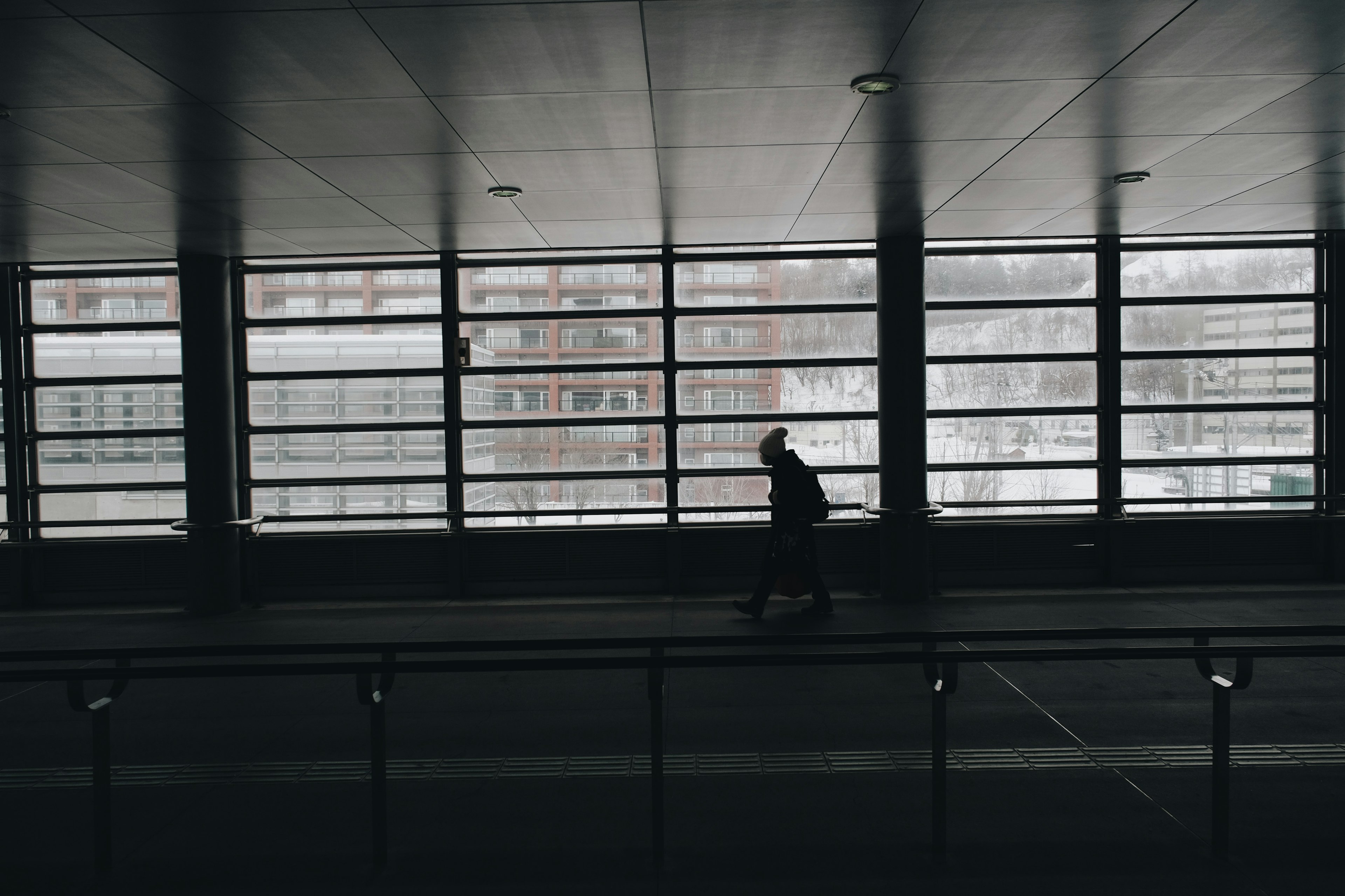 Silhouette of a person walking by large windows with a snowy background