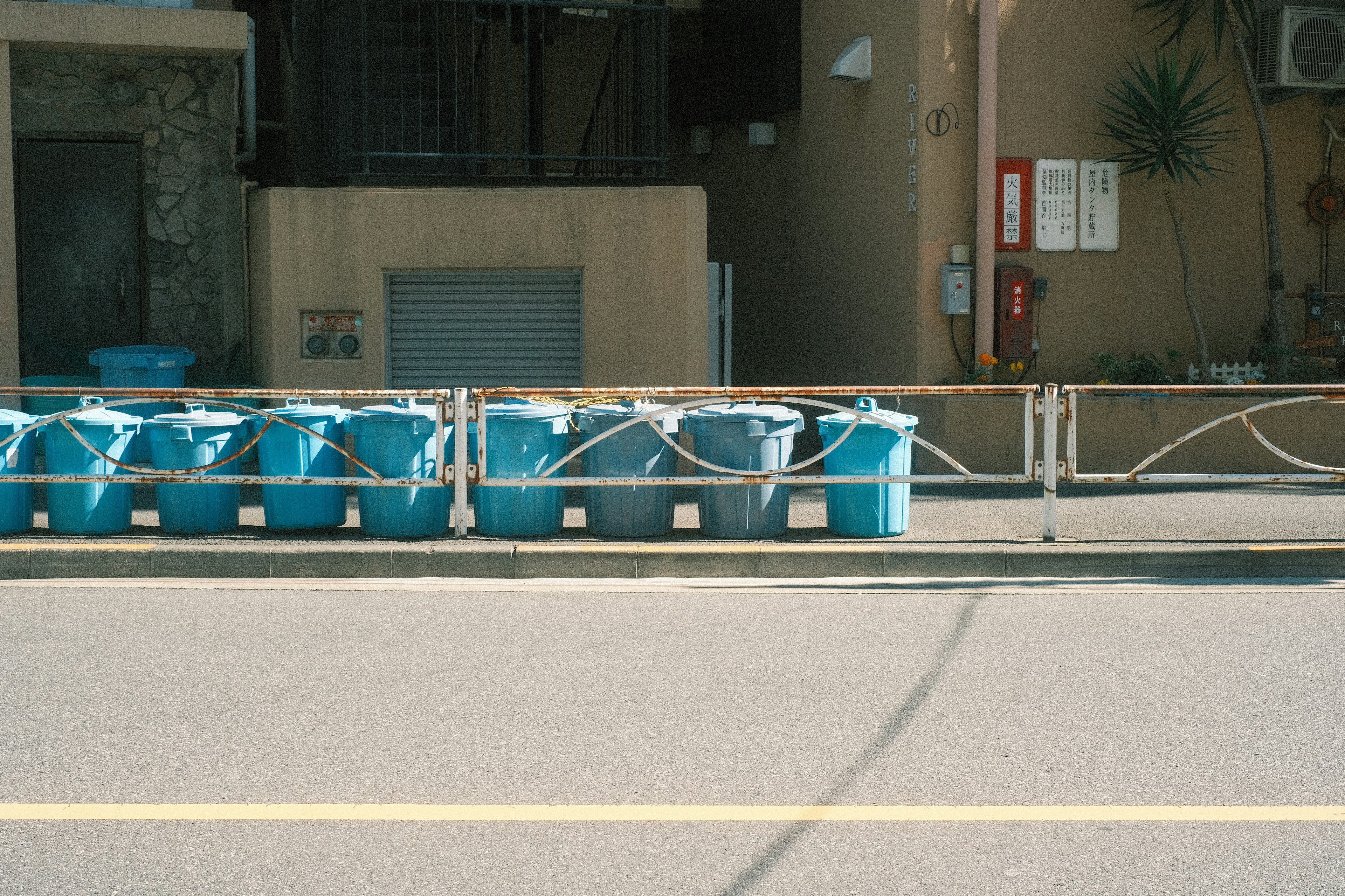 Fila de cubos de basura azules a lo largo de la calle