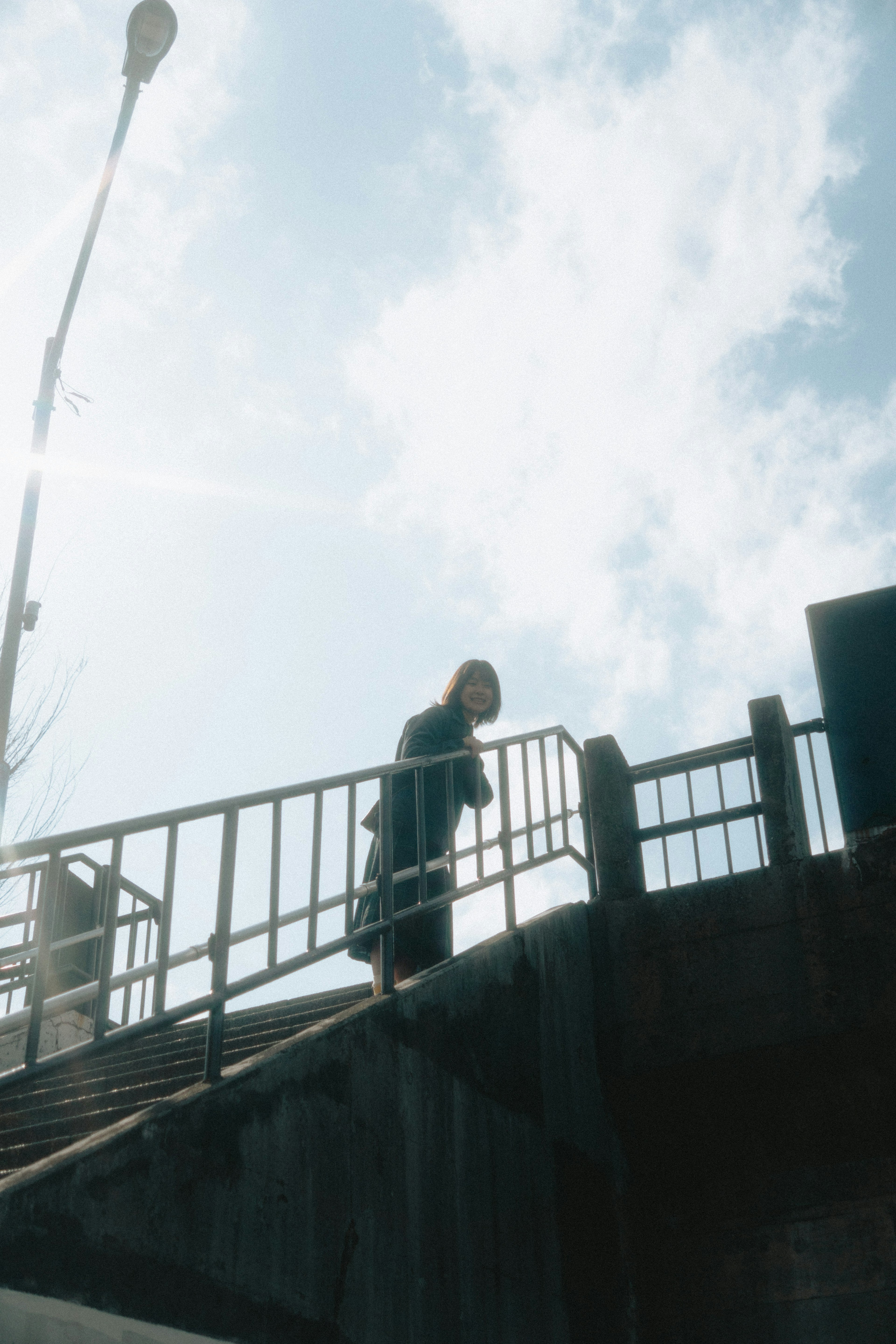 Eine Frau steht auf einer Brücke mit blauem Himmel im Hintergrund