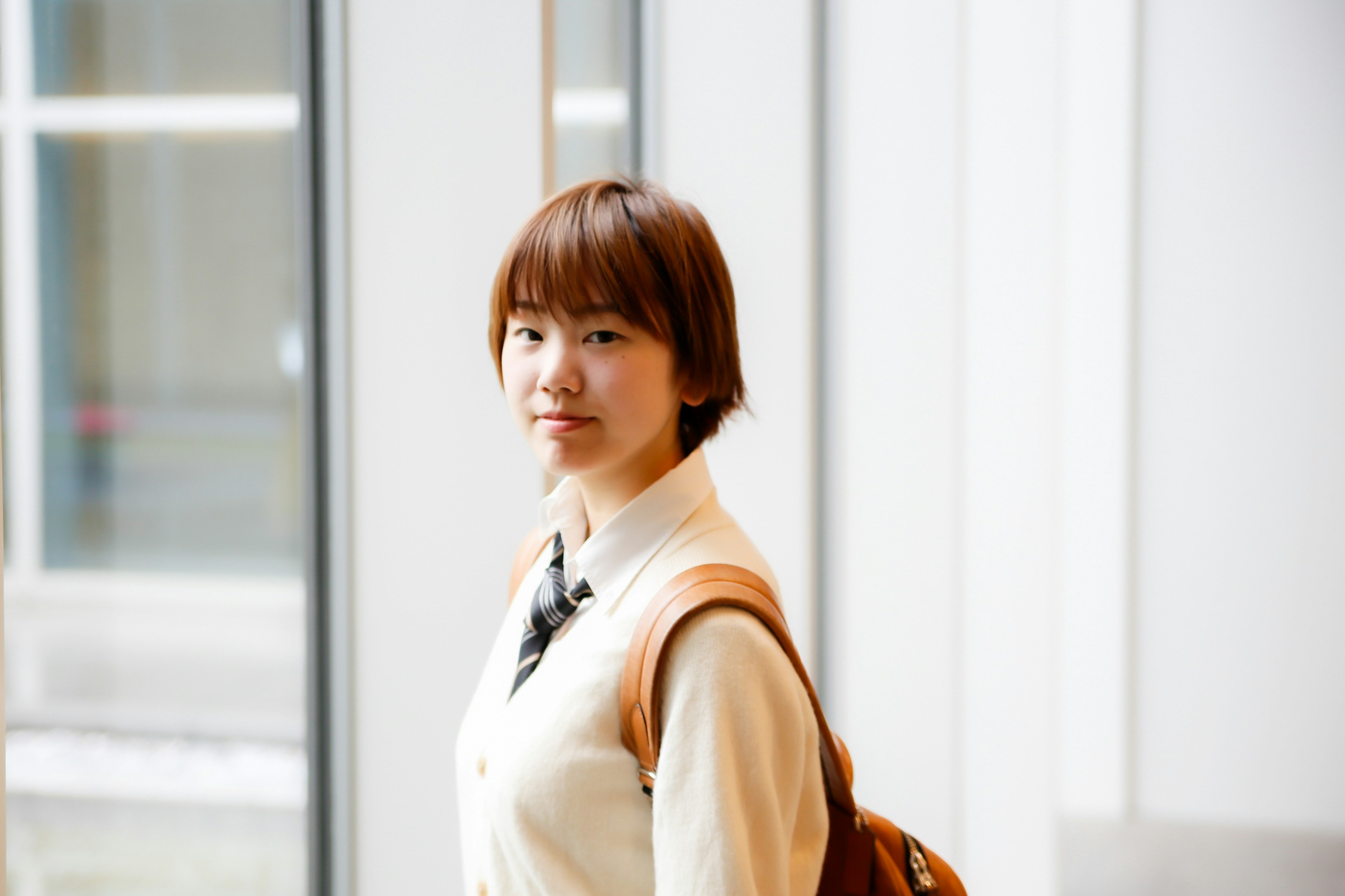 Portrait of a woman standing by a window with short hair and light clothing