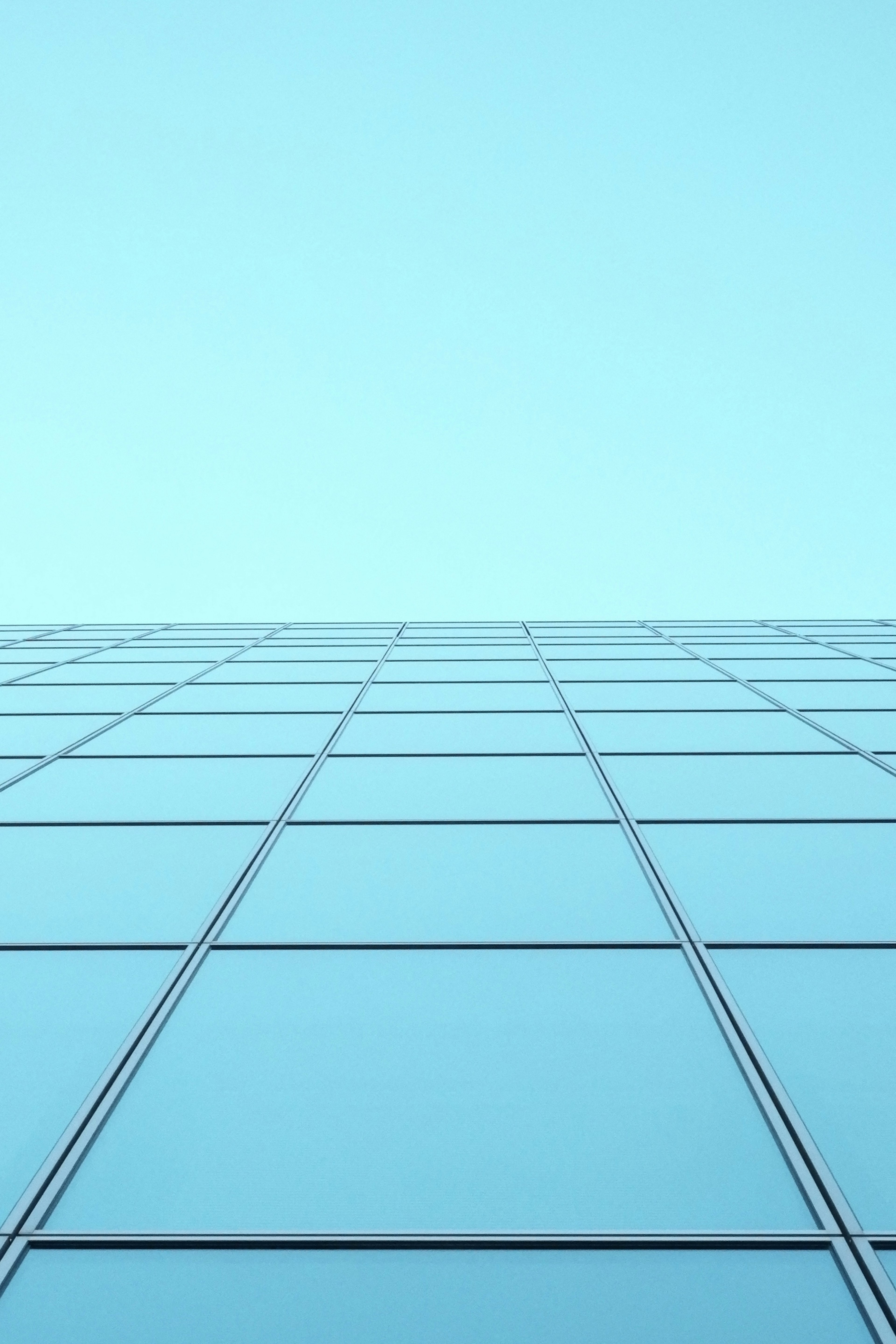 Façade d'un bâtiment en verre contre un ciel bleu avec un motif de fenêtres en grille