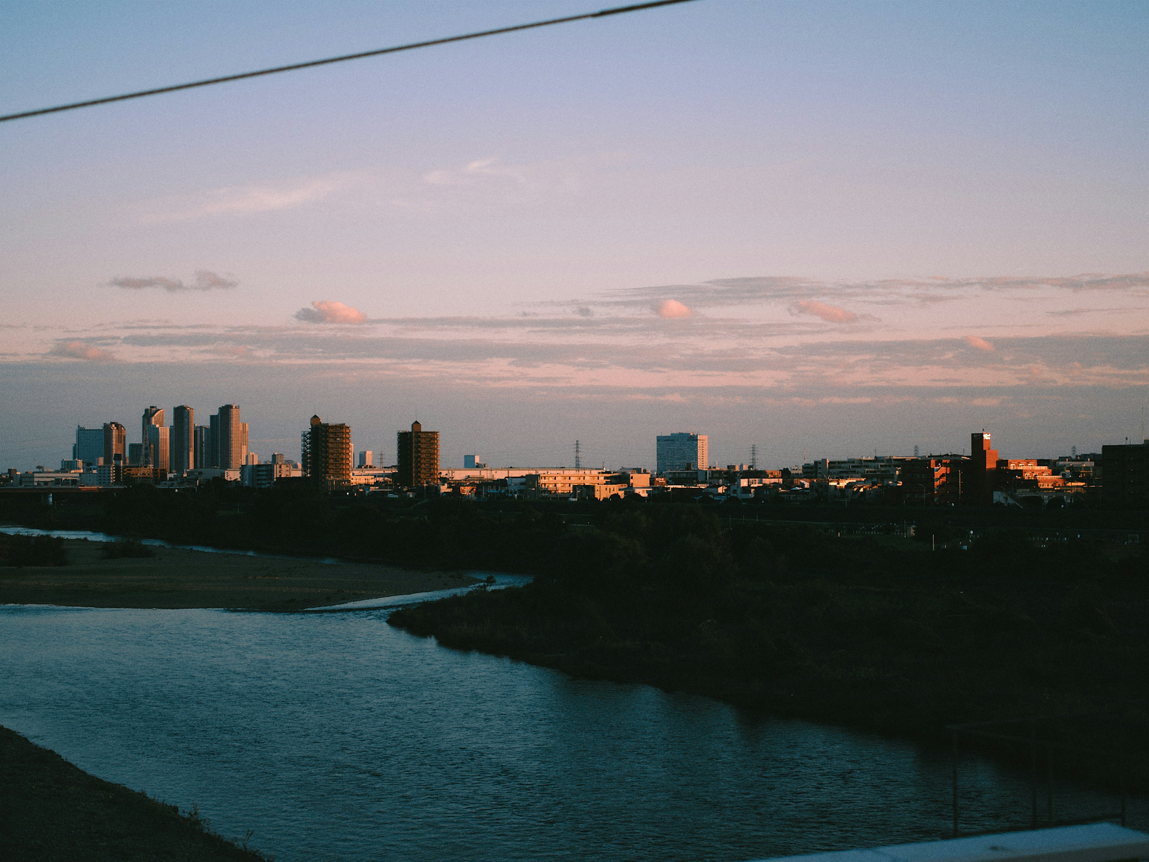 Vue du coucher de soleil sur une rivière avec une ligne d'horizon de la ville en arrière-plan