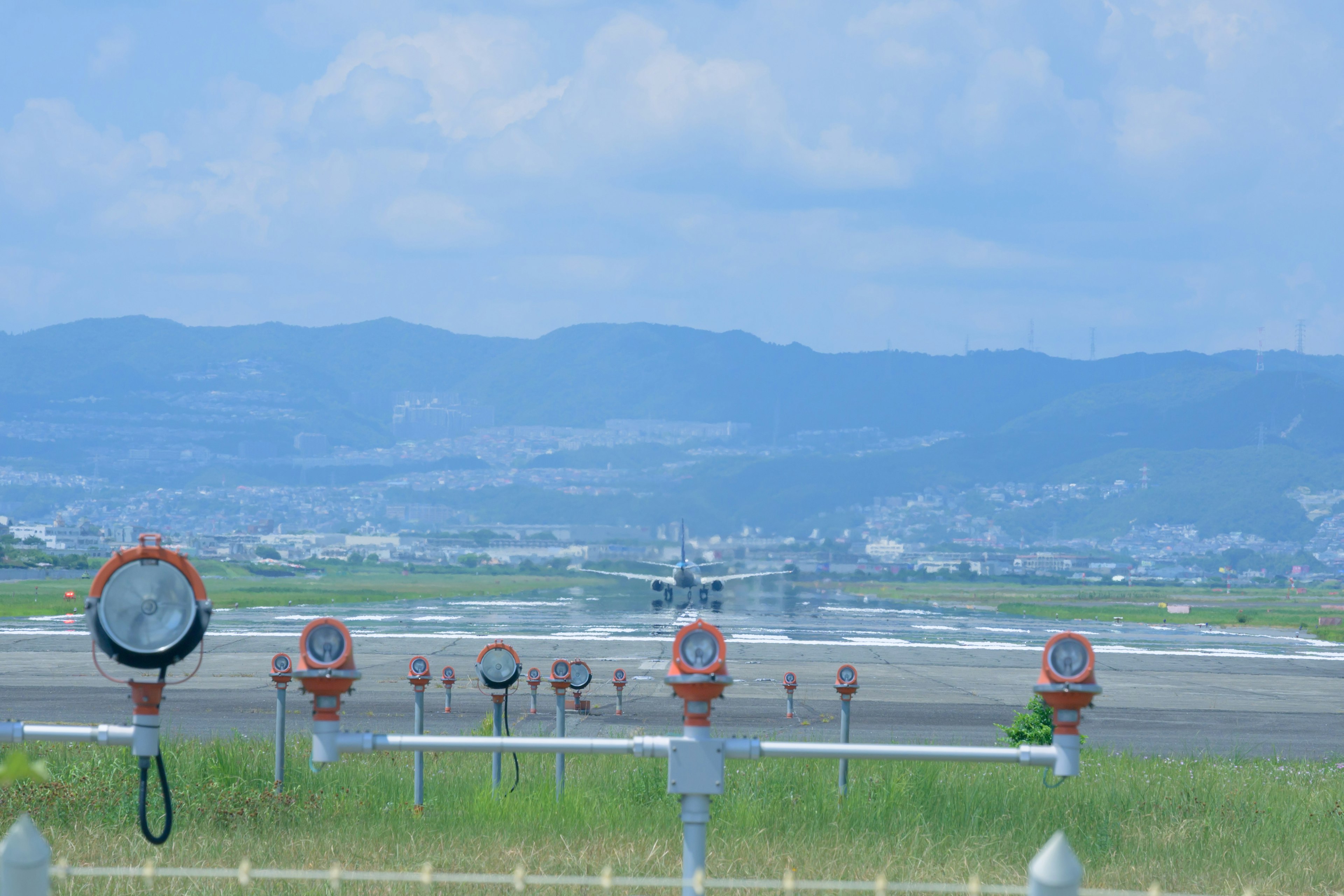 Avión aterrizando en una pista con luces de pista y montañas al fondo