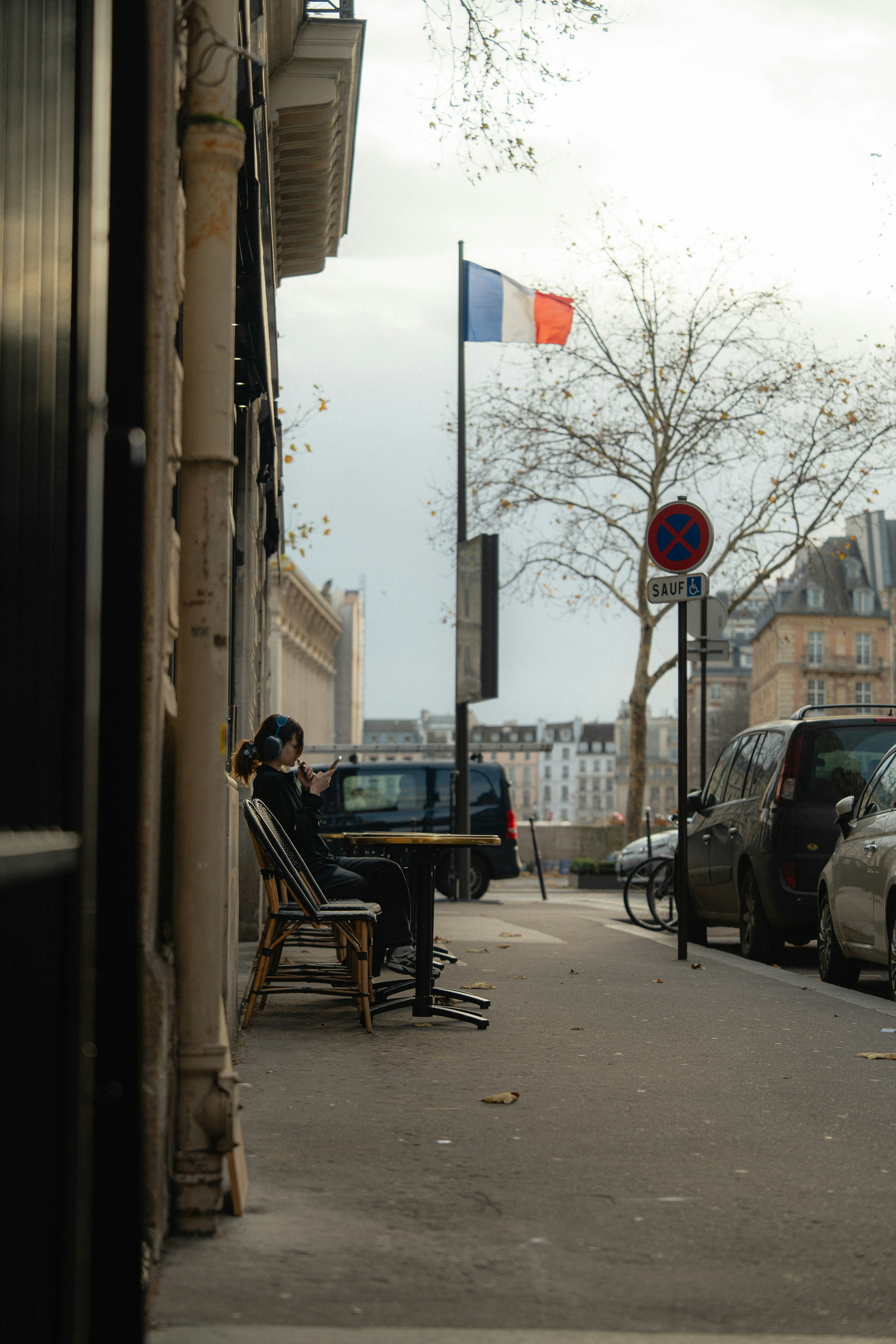 Una persona seduta a un angolo di strada a Parigi con una bandiera francese